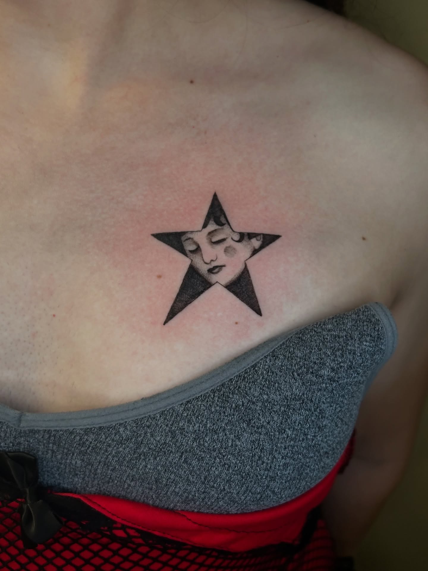 Star with woman's face black and grey tattoo on the chest by Cassy D, Miami, Florida