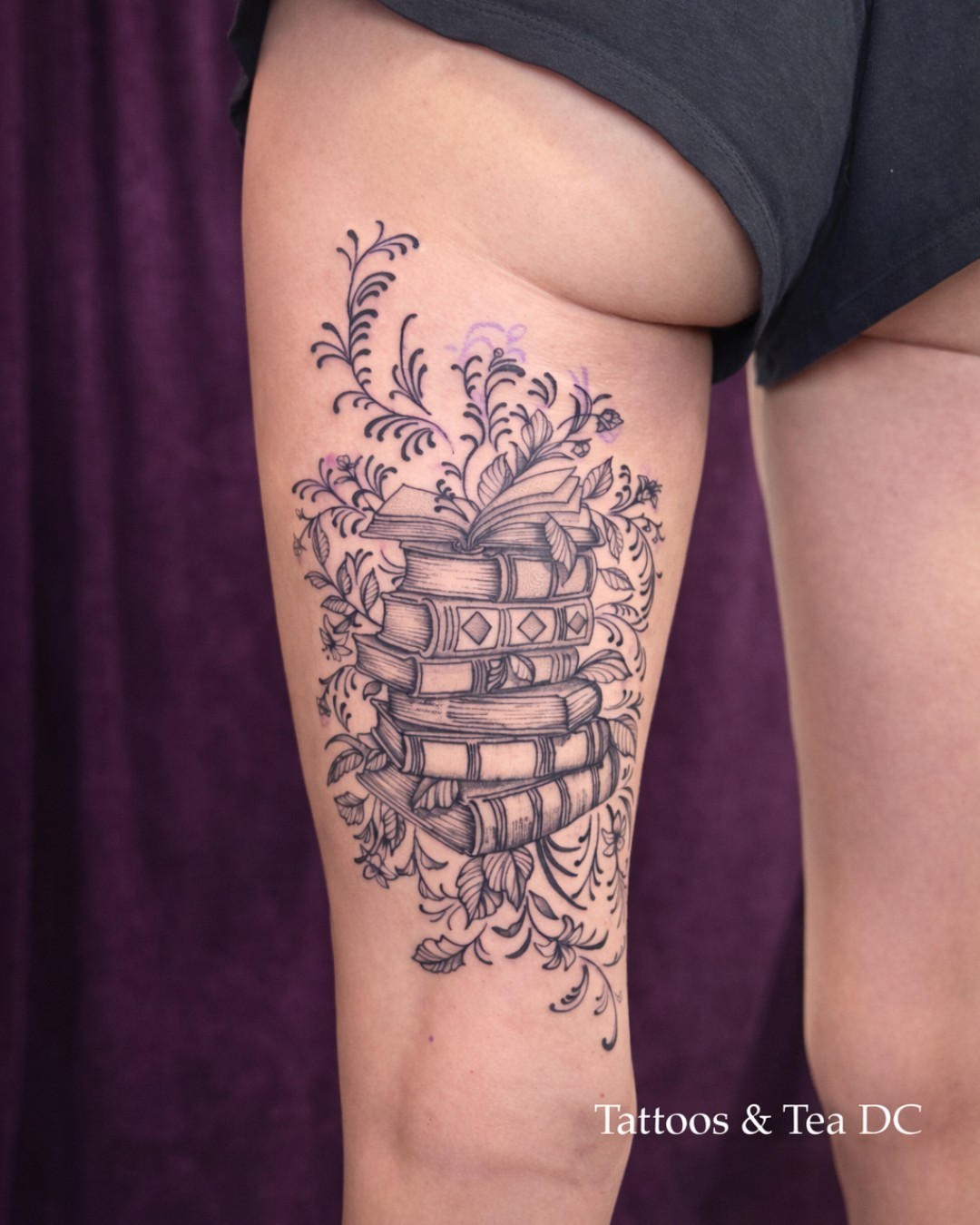 Stacked books with floral ornamentation ornamental tattoo on the thigh by Tattoos & Tea DC, Arlington, Virginia
