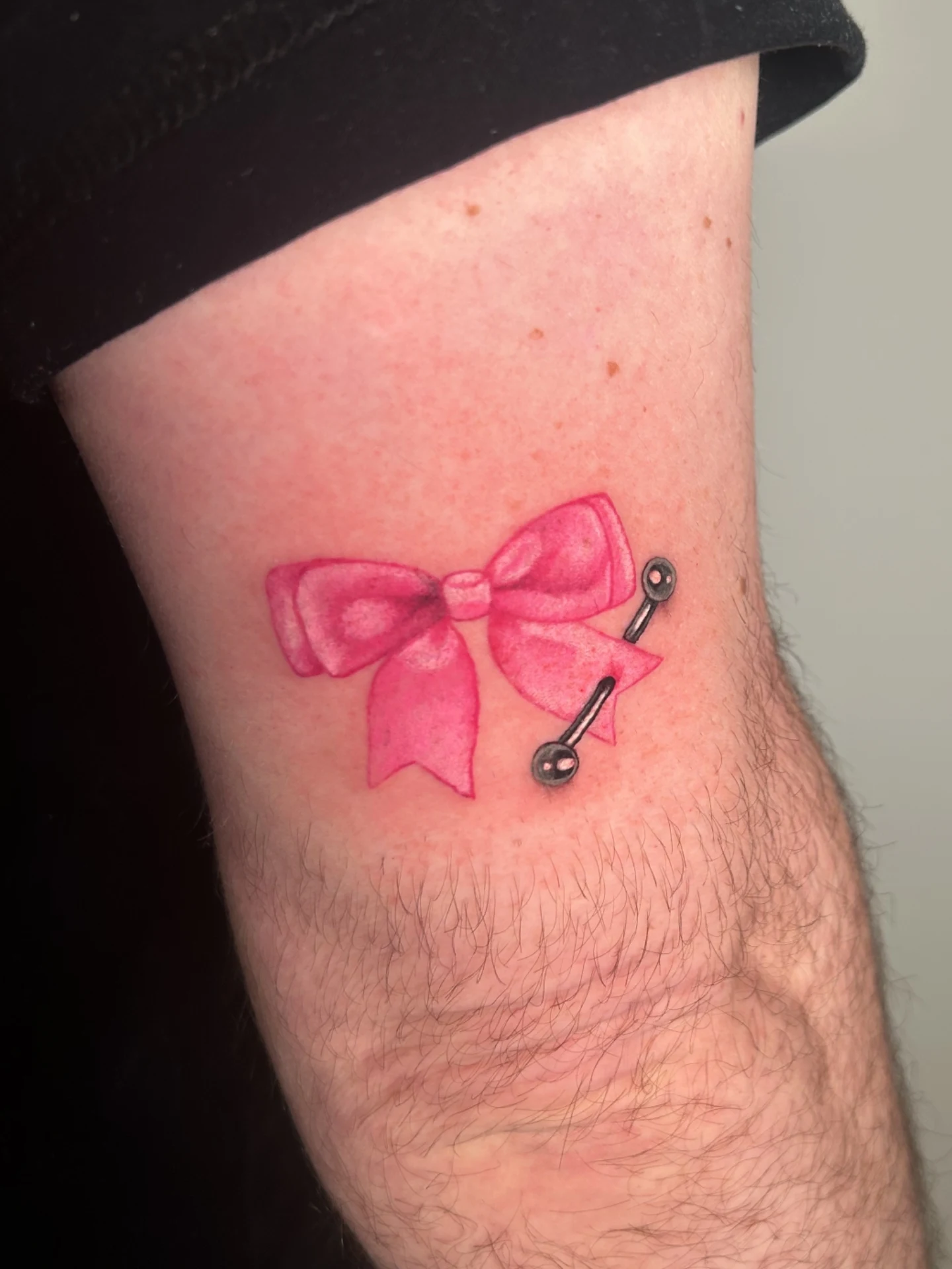 Bow and barbell watercolor tattoo on the forearm by Chloe Marie