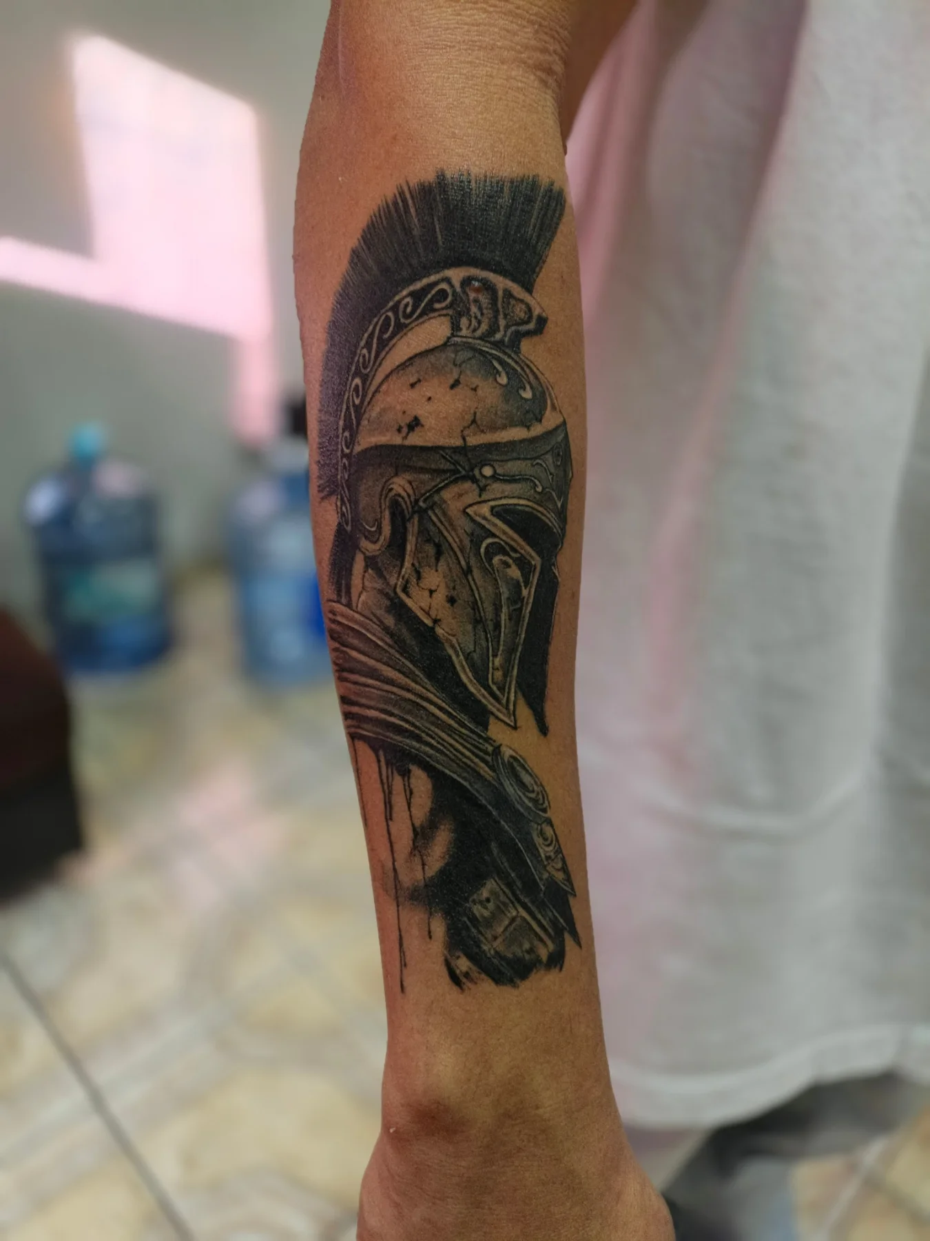Spartan helmet black and grey tattoo on the forearm by Alexander Tattooink