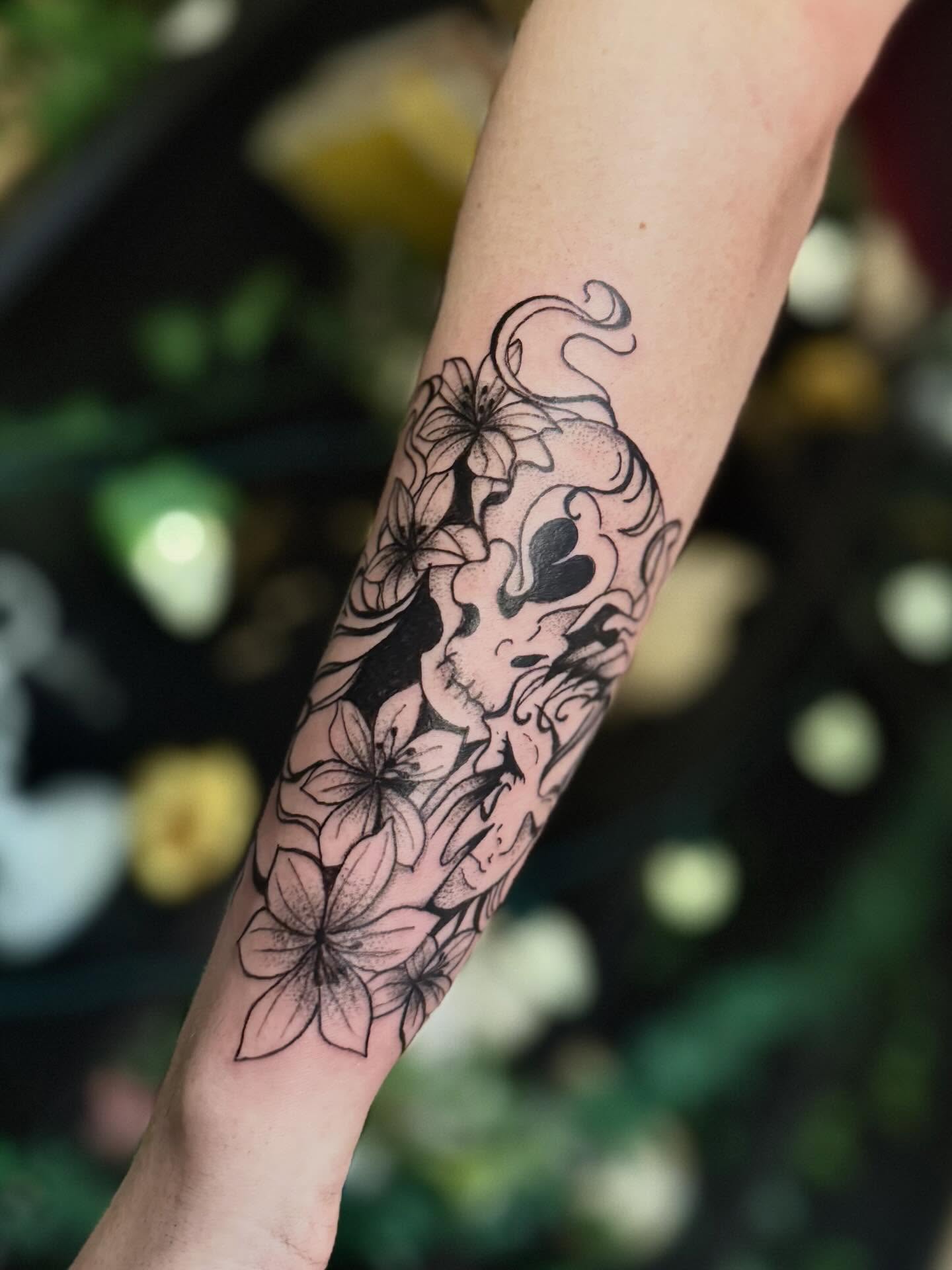 Skull and flowers black and grey tattoo on the forearm by Haley Bates