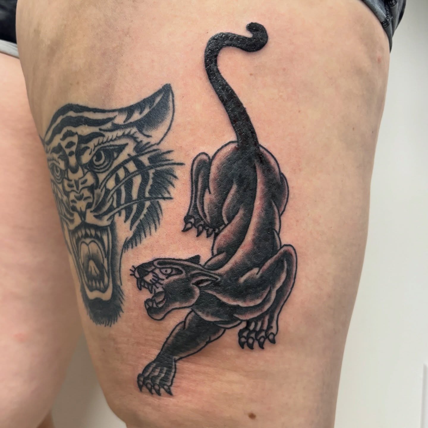 Panther and tiger black and grey tattoo on the thigh by Bridget Smith