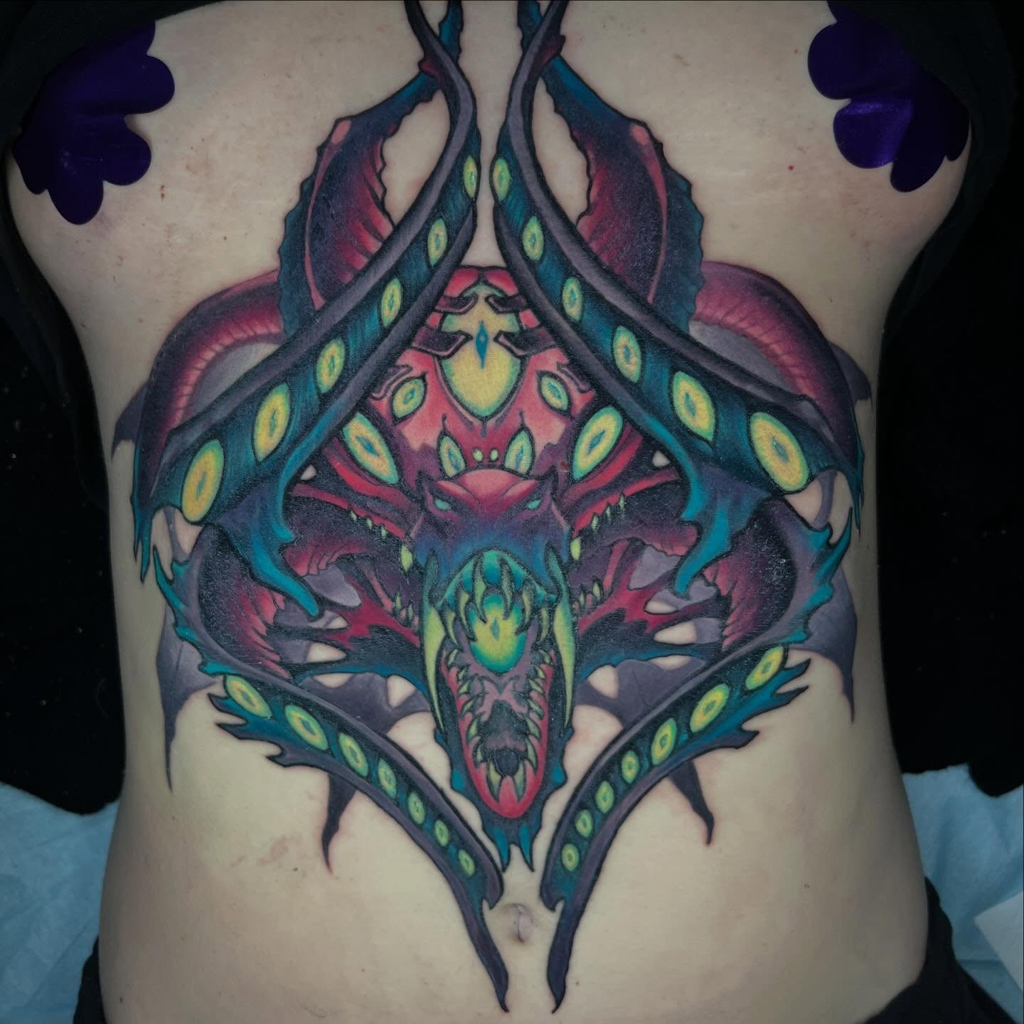 Alien creature geometric tattoo on the ribs by Kate Erso