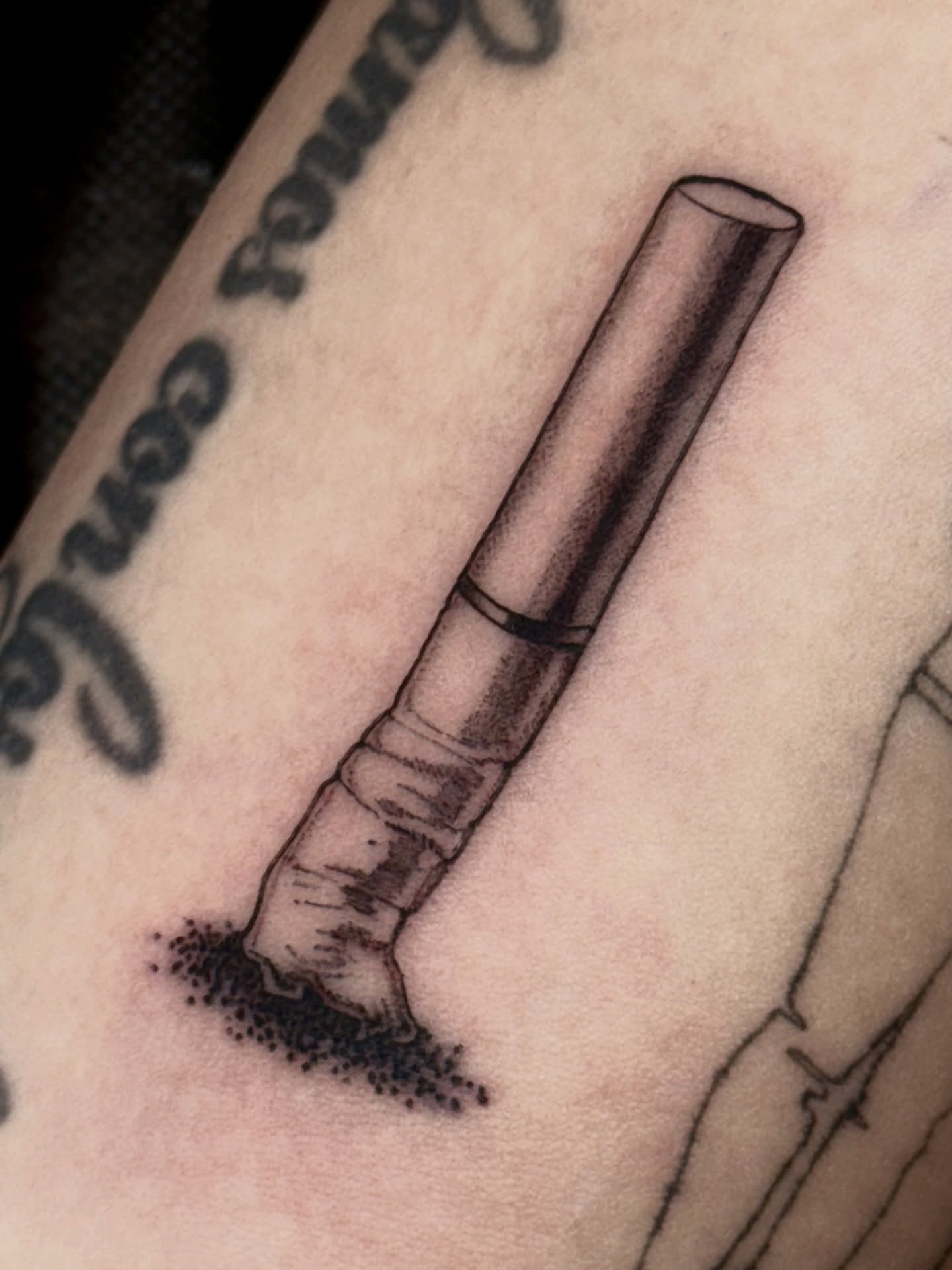 Cigarette butt black and grey tattoo on the forearm by Lydia Jude