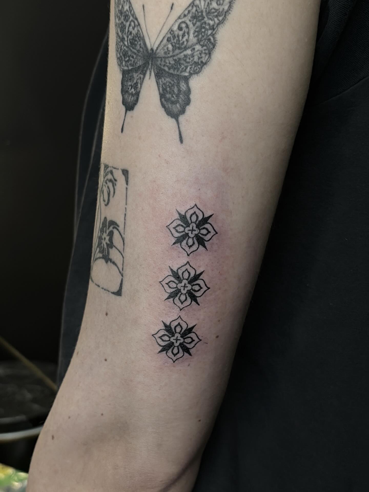 Butterfly and flowers black and grey tattoo on the forearm by Harlee Hornsby