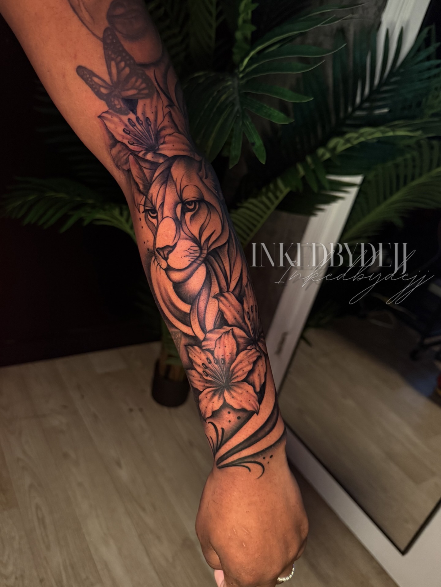 Lion and flowers realism tattoo on the forearm by Inkedbydejj