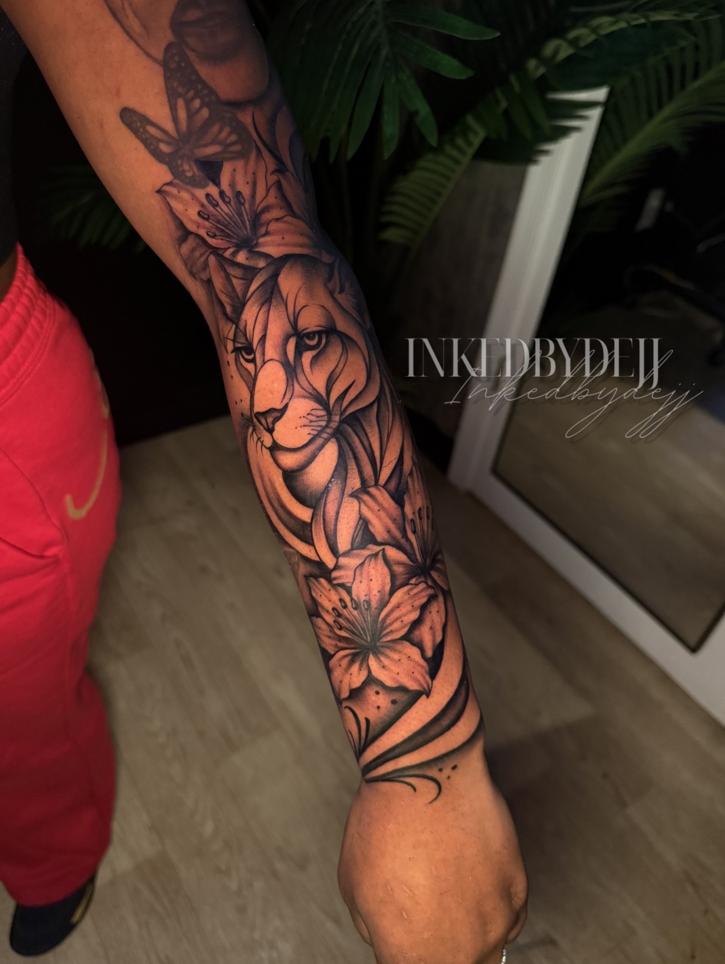 Lion and flowers realism tattoo on the forearm by Inkedbydejj