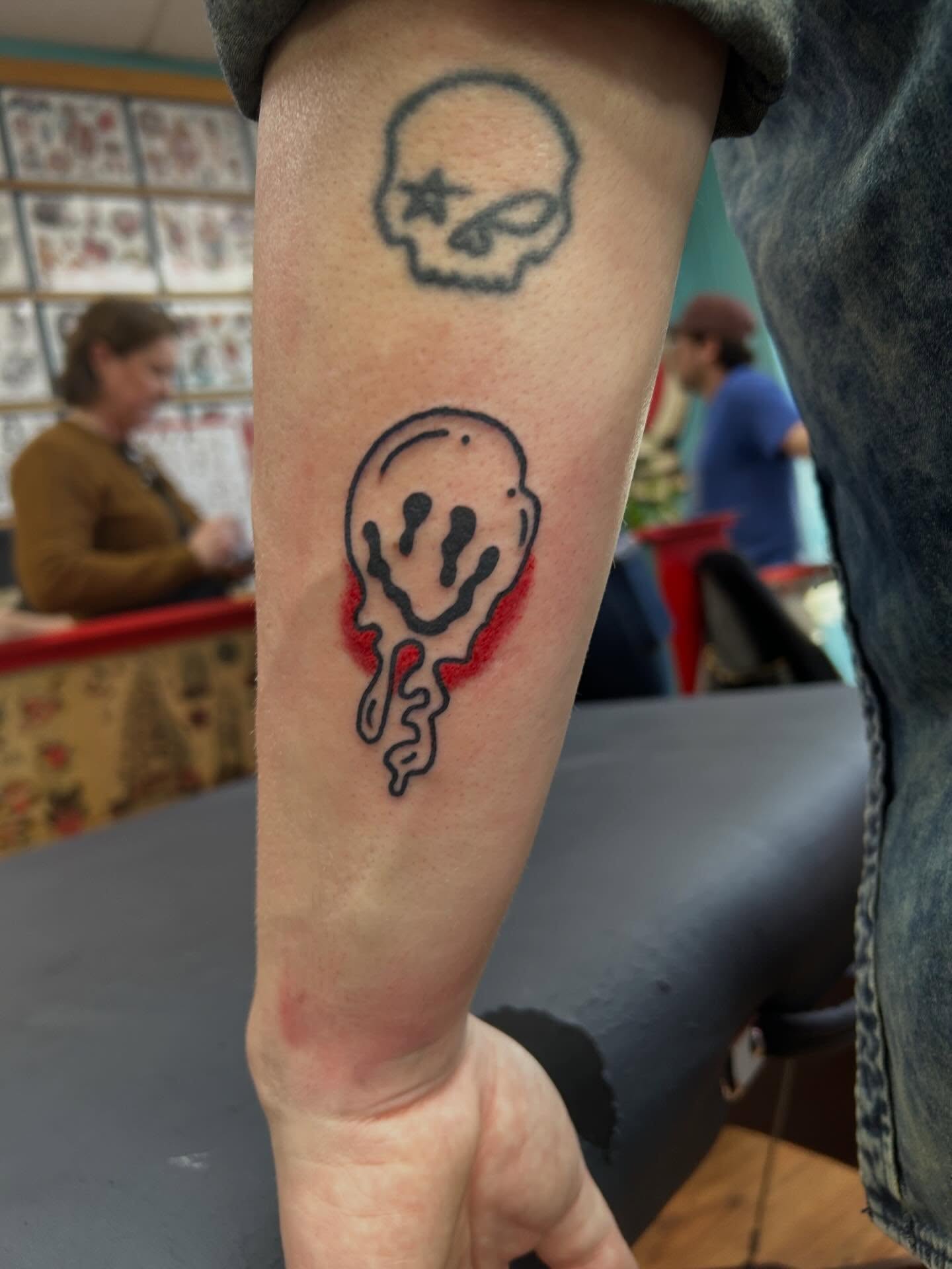 Smiley face dotwork tattoo on the forearm by Elizabeth Niederkorn
