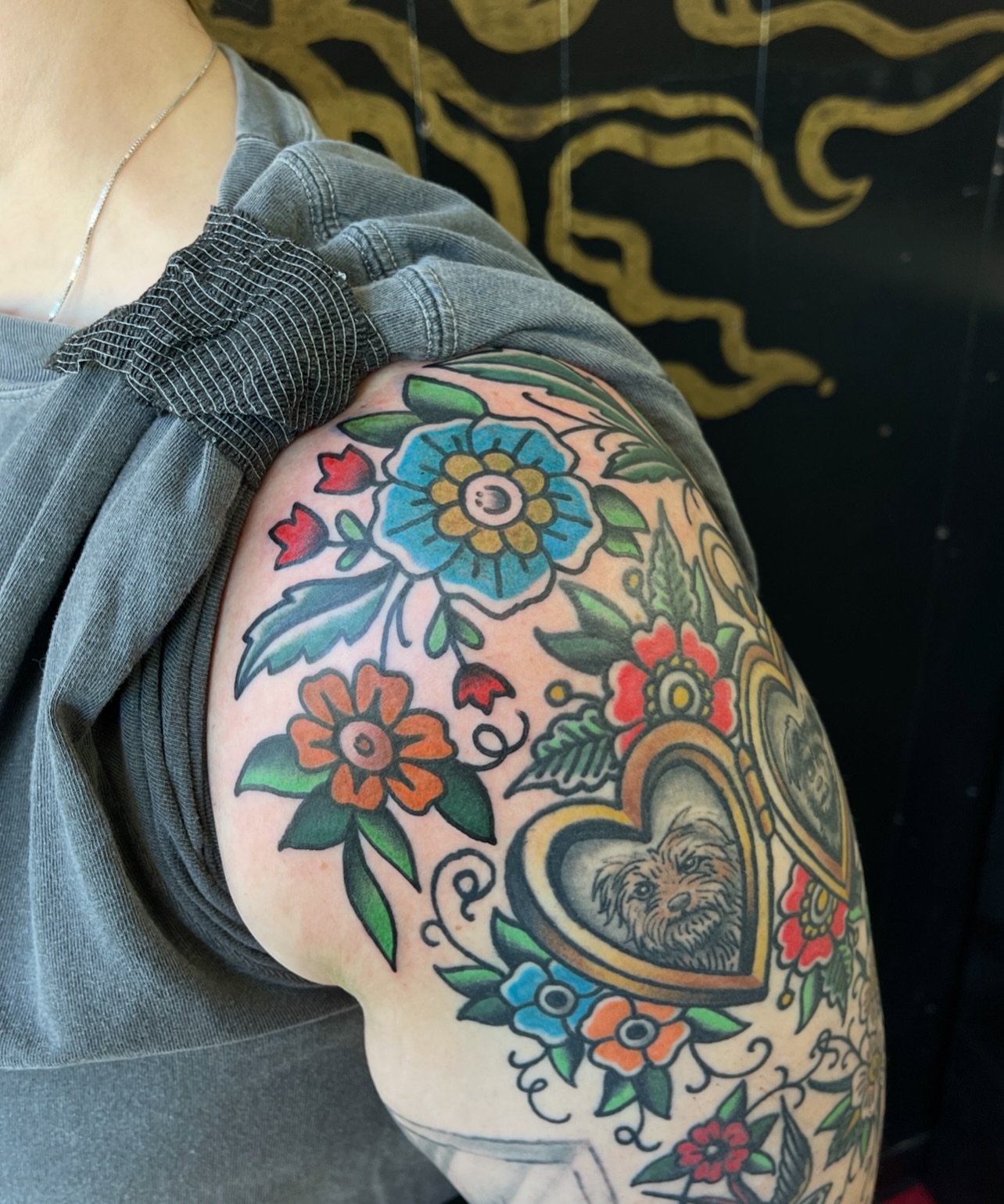 Floral arrangement with dog American traditional tattoo on the shoulder by Patrick Miller, Huber Heights, Ohio