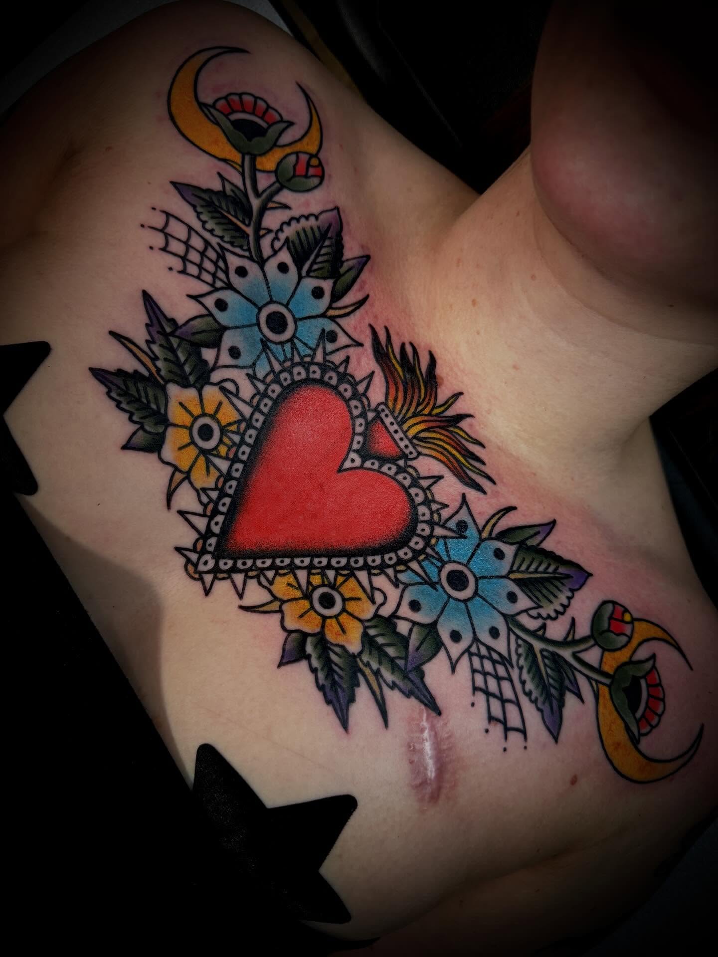 Heart with floral elements American traditional tattoo on the chest by Andrew Slater