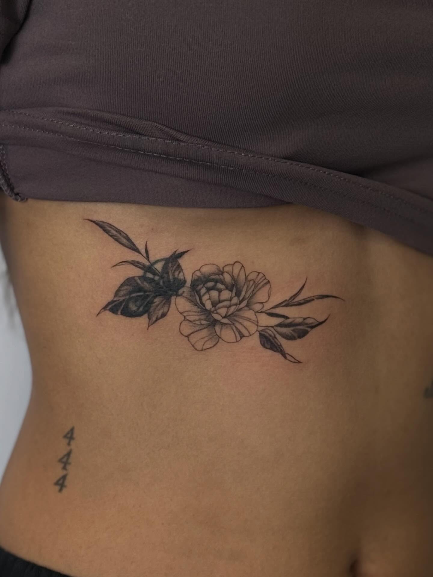 Flower and leaves black and grey tattoo on the ribs by Nevaeh tattoo artist