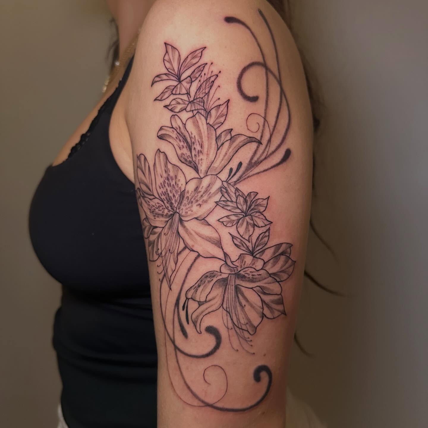 Lilies black and grey tattoo on the upper arm by Nia Malone (Knee-Uh)