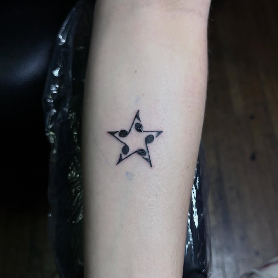 Star with musical notes fine line tattoo on the forearm by Angel Arceo