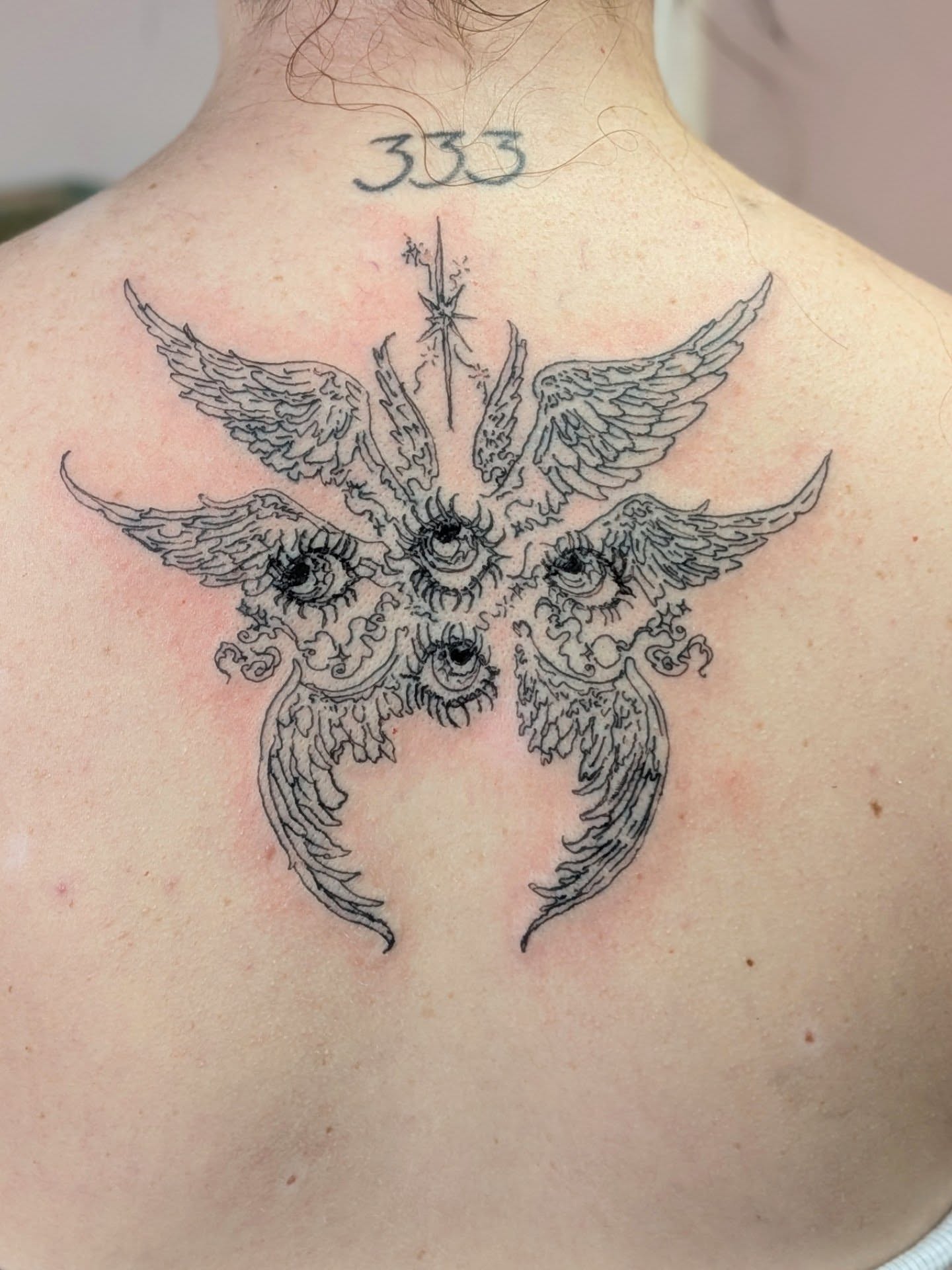 Wings and eyes black and grey tattoo on the back by Ryan