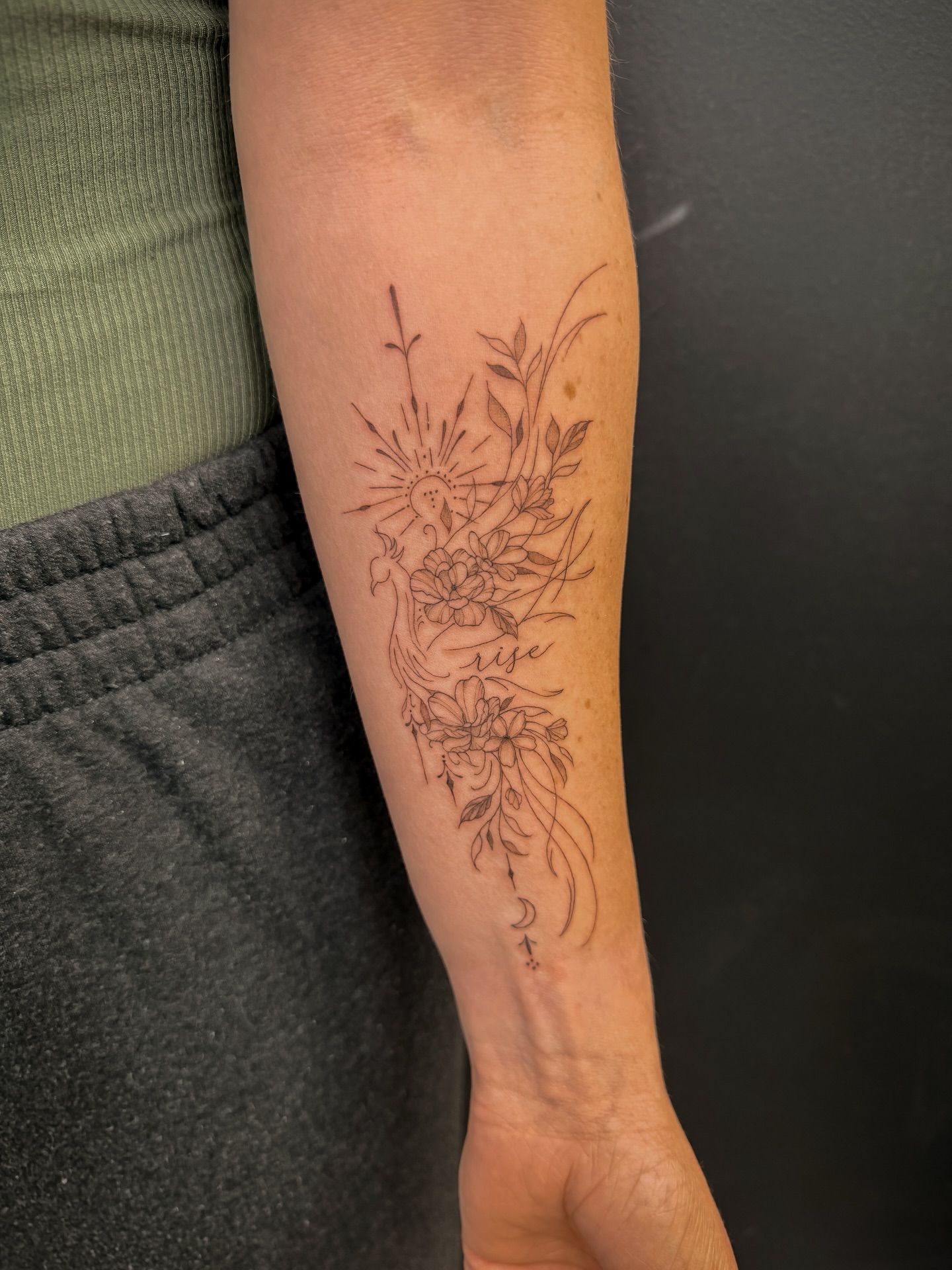 Floral and sun design fine line tattoo on the forearm by Reverie Studio