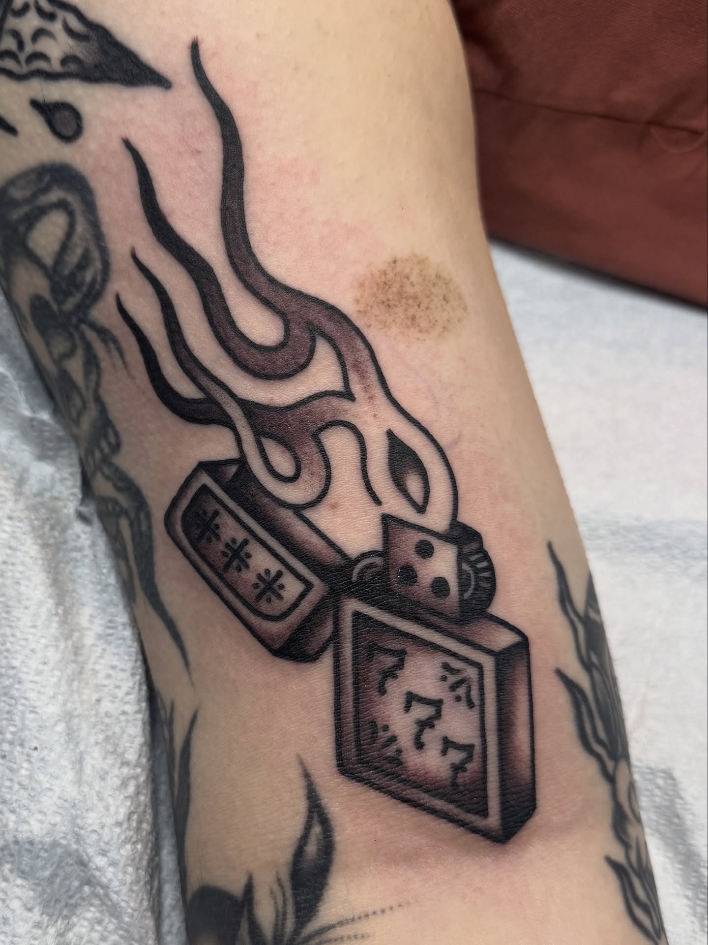 Lighter with flames black and grey tattoo on the forearm by Nicholas Tidler