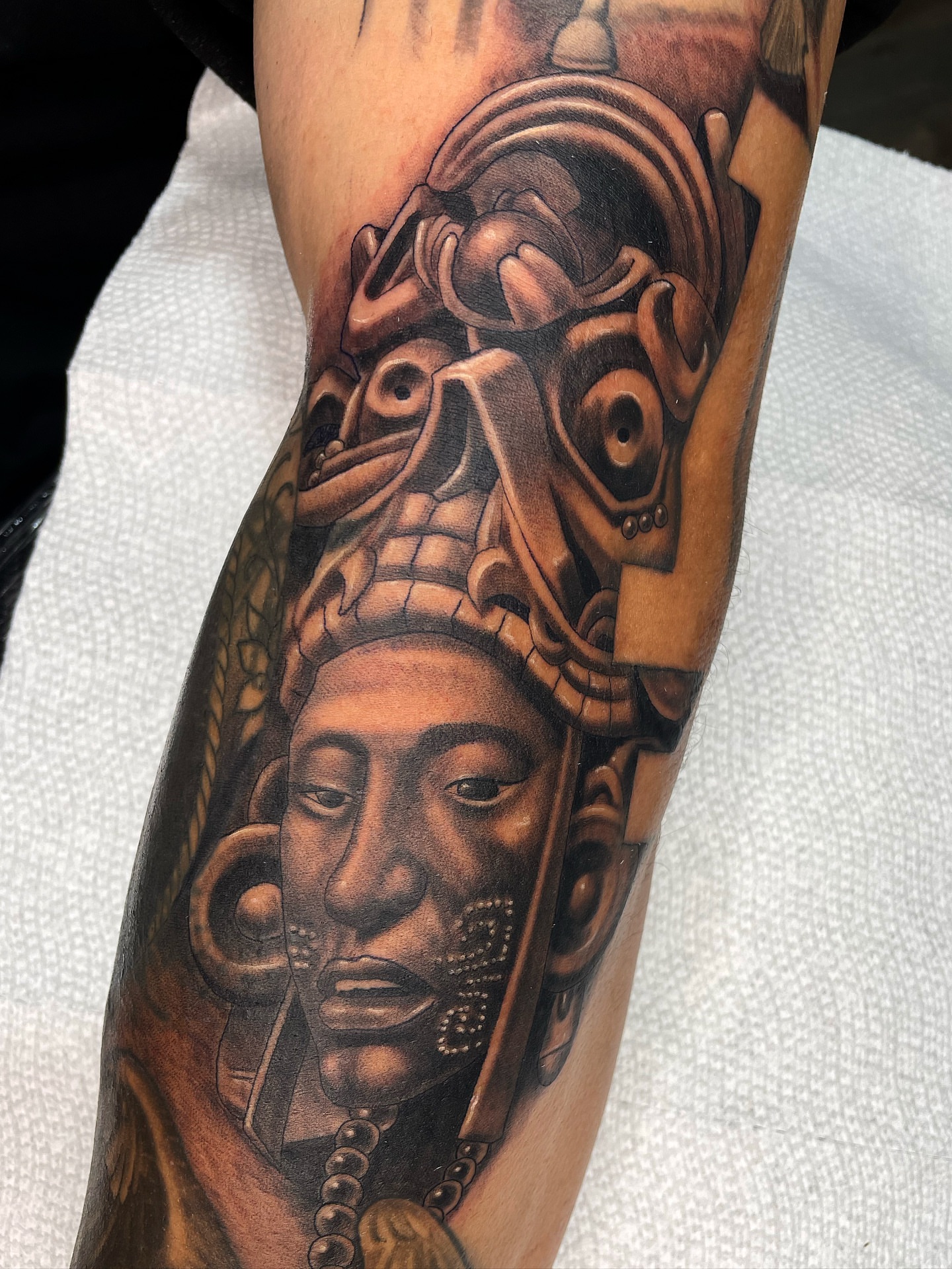 Ancient mask realism tattoo on the forearm by Alex Ortiz