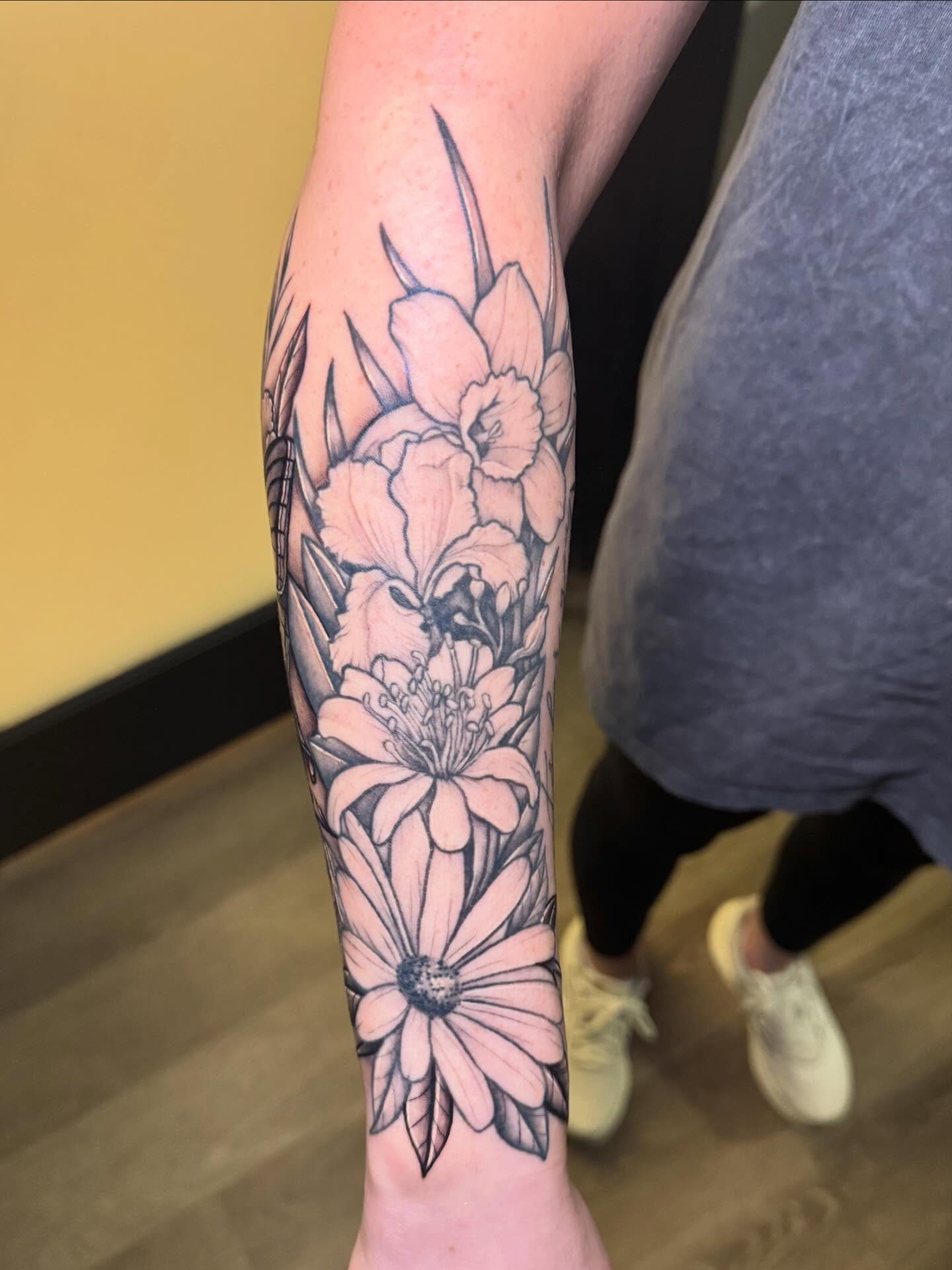Floral arrangement black and grey tattoo on the forearm by Madison Pegram