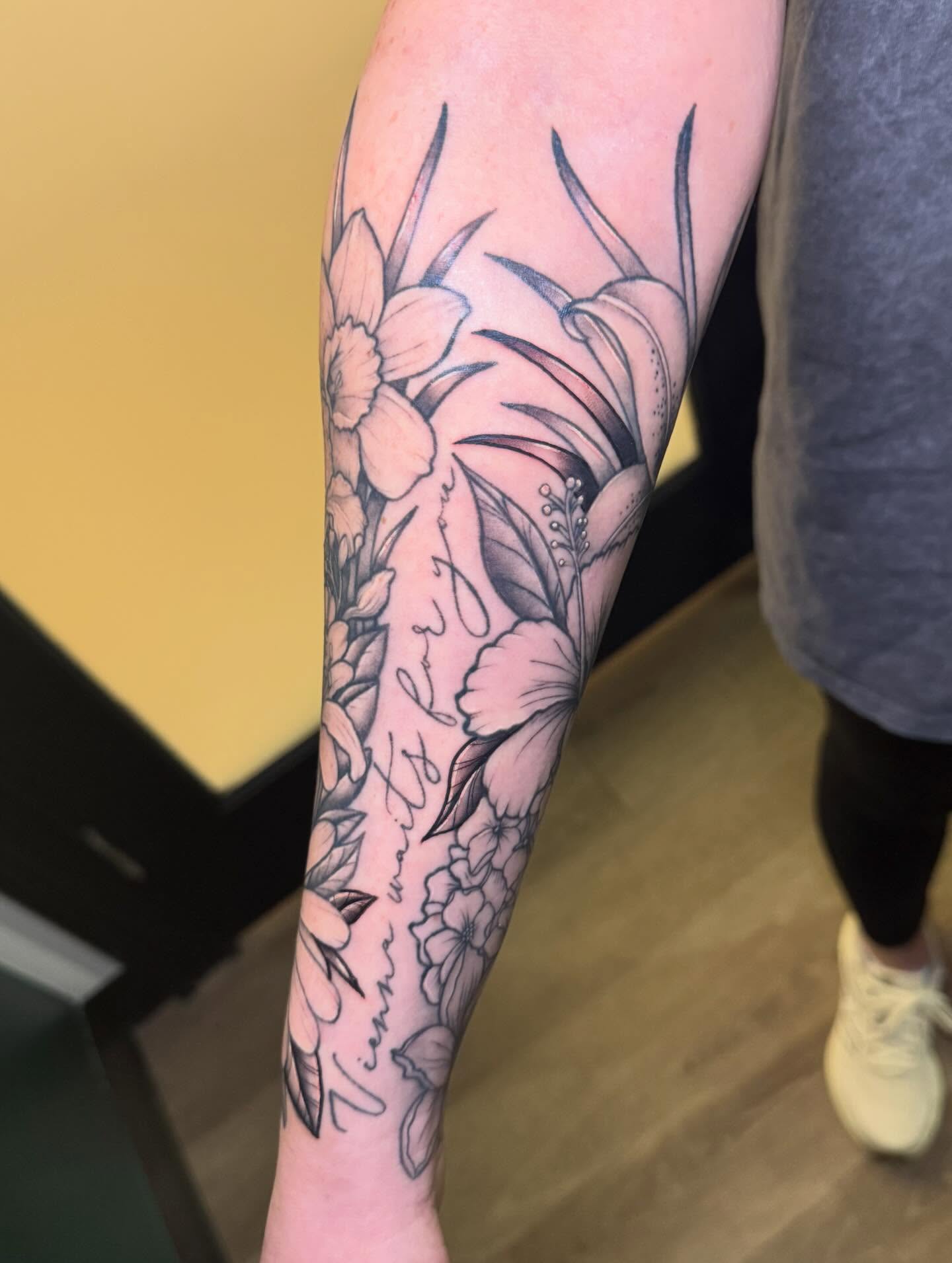 Floral arrangement black and grey tattoo on the forearm by Madison Pegram