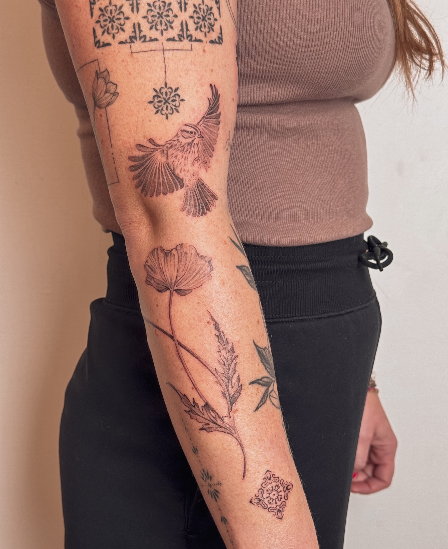 Bird and flowers black and grey tattoo on the forearm by Floral