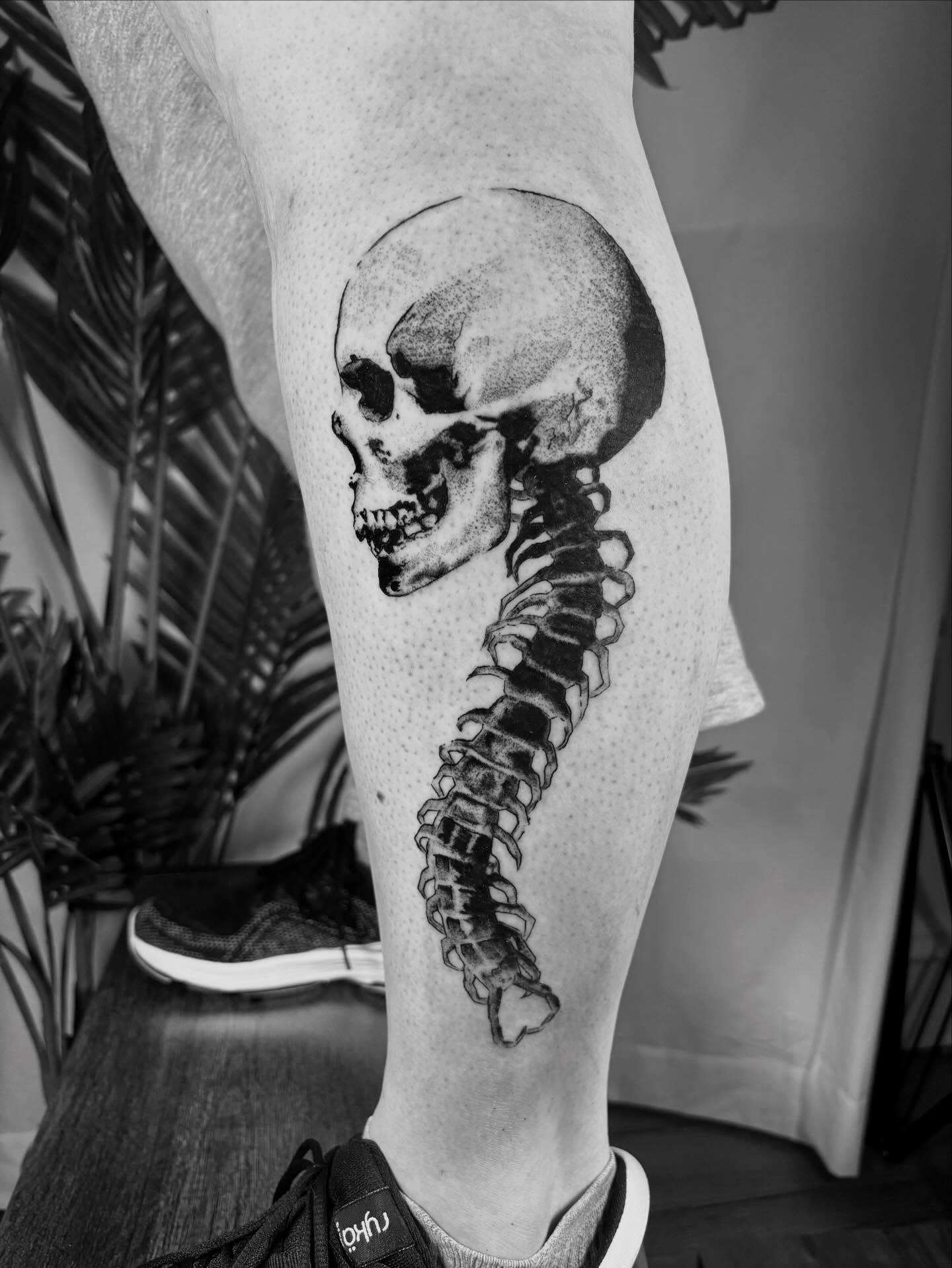 Skull and spine dotwork tattoo on the calf by Davie Tattoos