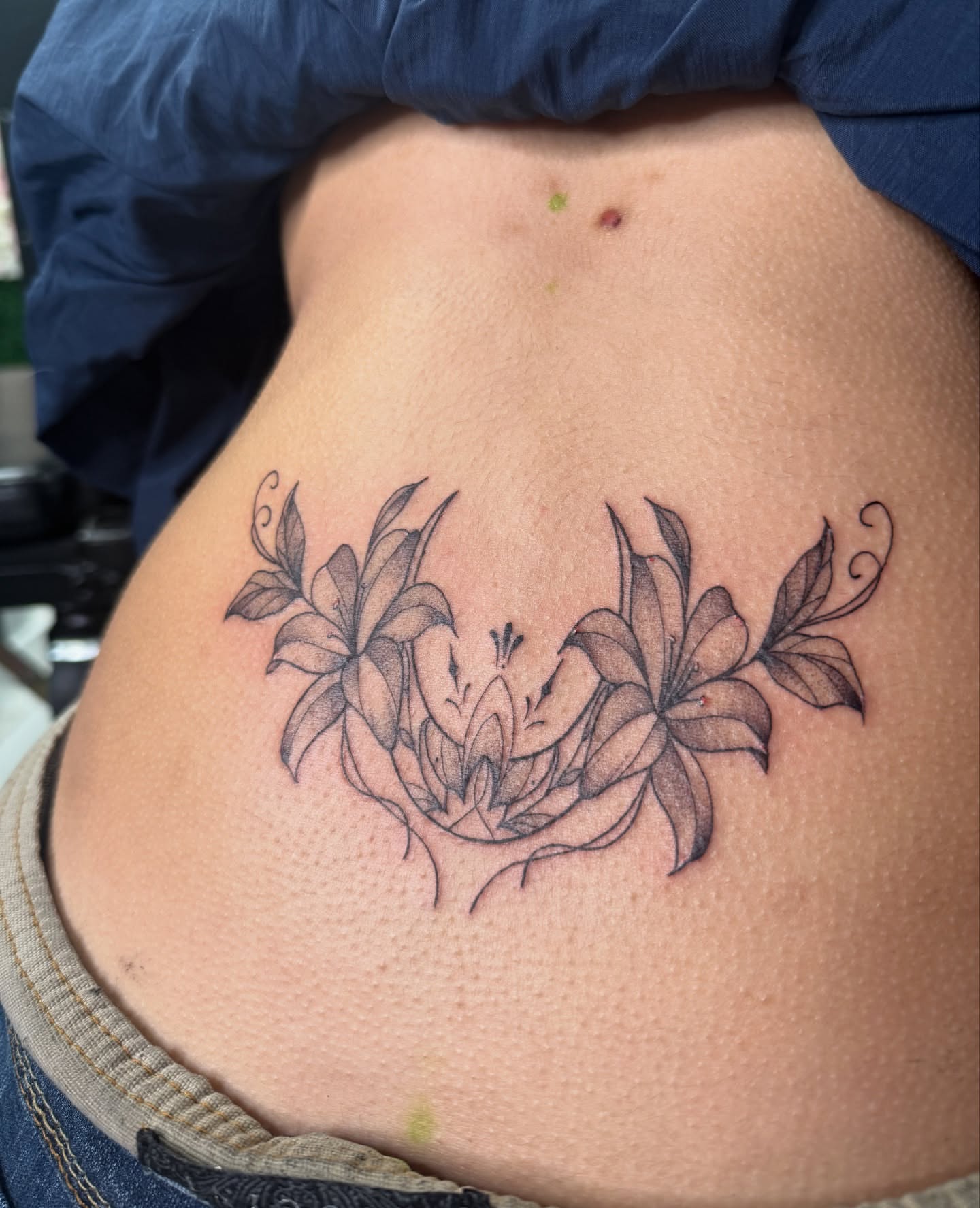 Lilies black and grey tattoo on the ribs by Tattoo Artist