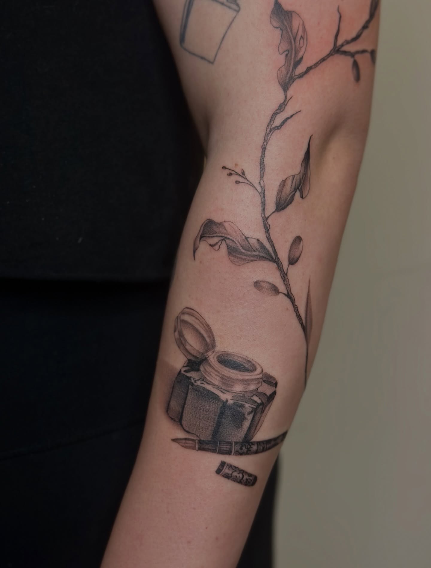 Inkwell and pen realism tattoo on the forearm by Macy Rae