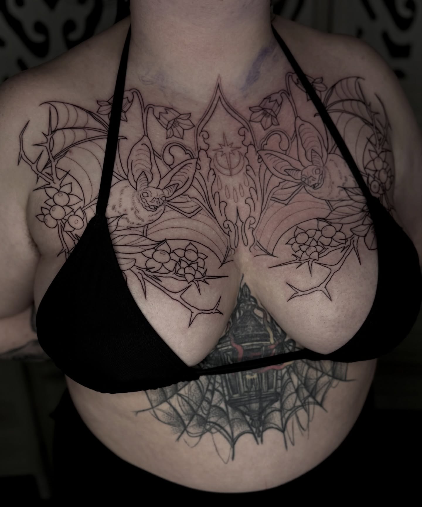 Floral and bat black and grey tattoo on the chest by Emersyn DeLuna