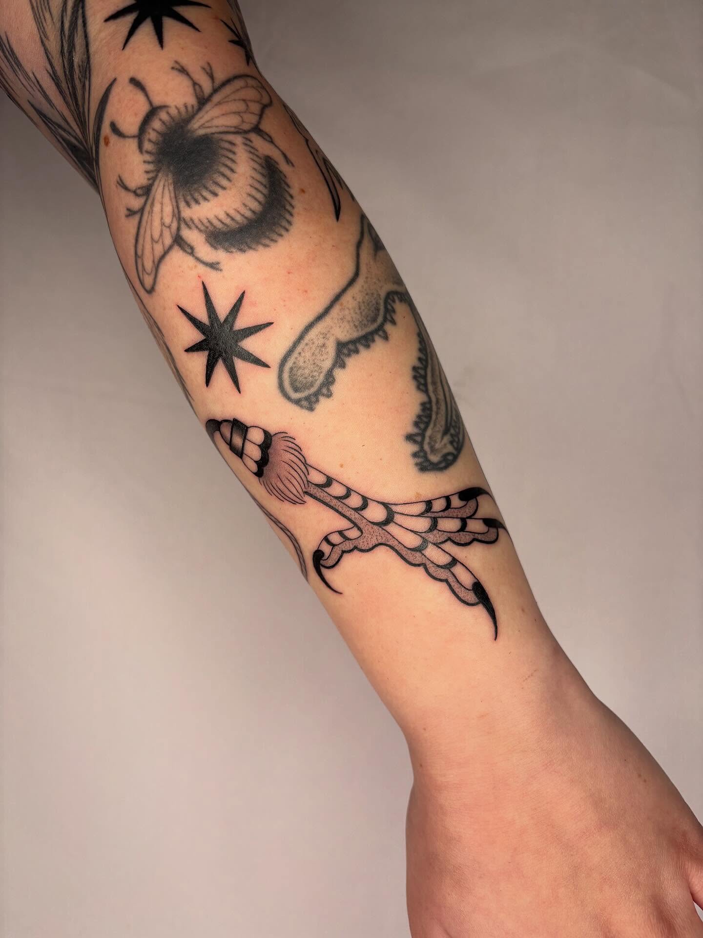 Insect and star black and grey tattoo on the forearm by Victoria Bacon