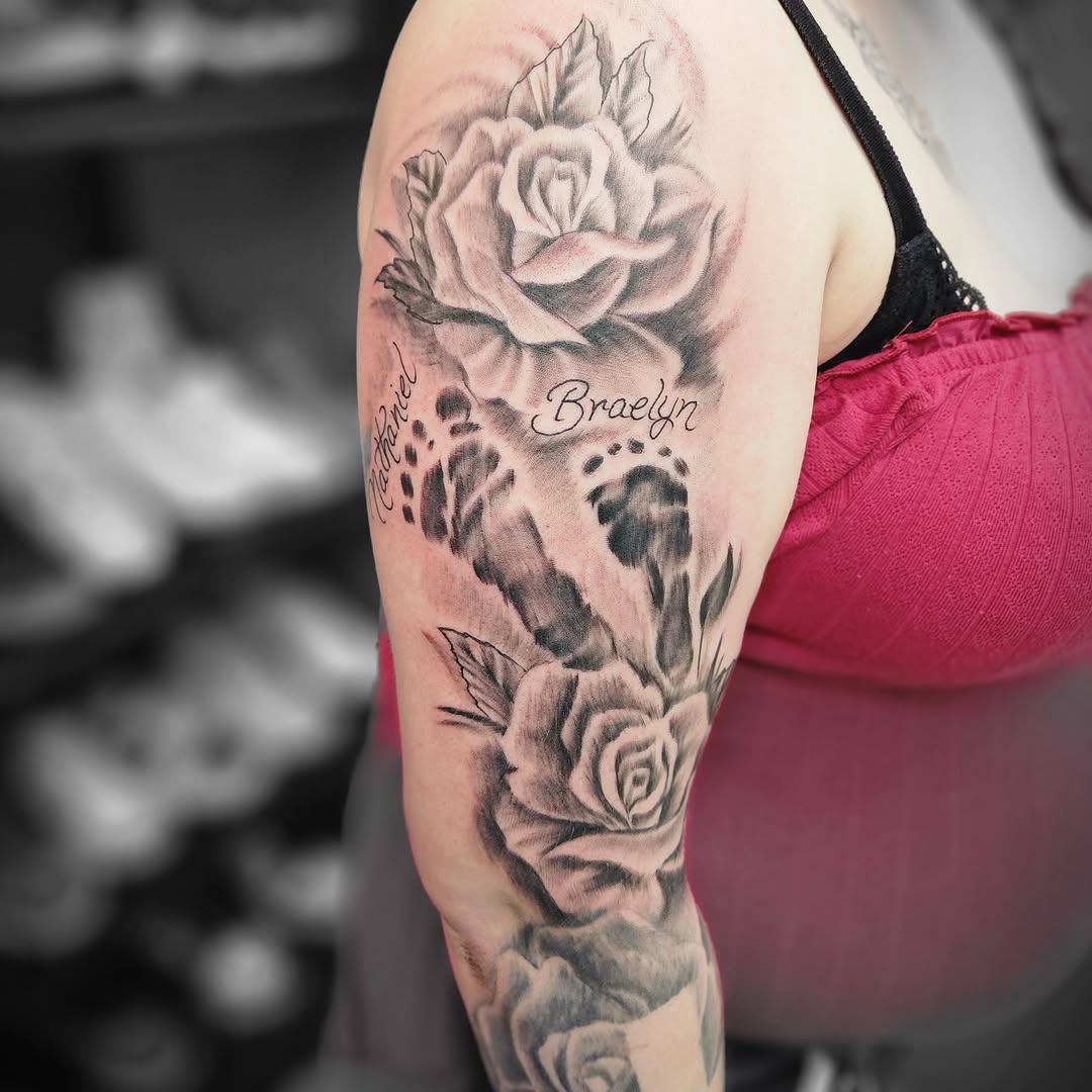 Roses and footprints with names Chicano tattoo on the forearm by Dennis Foust