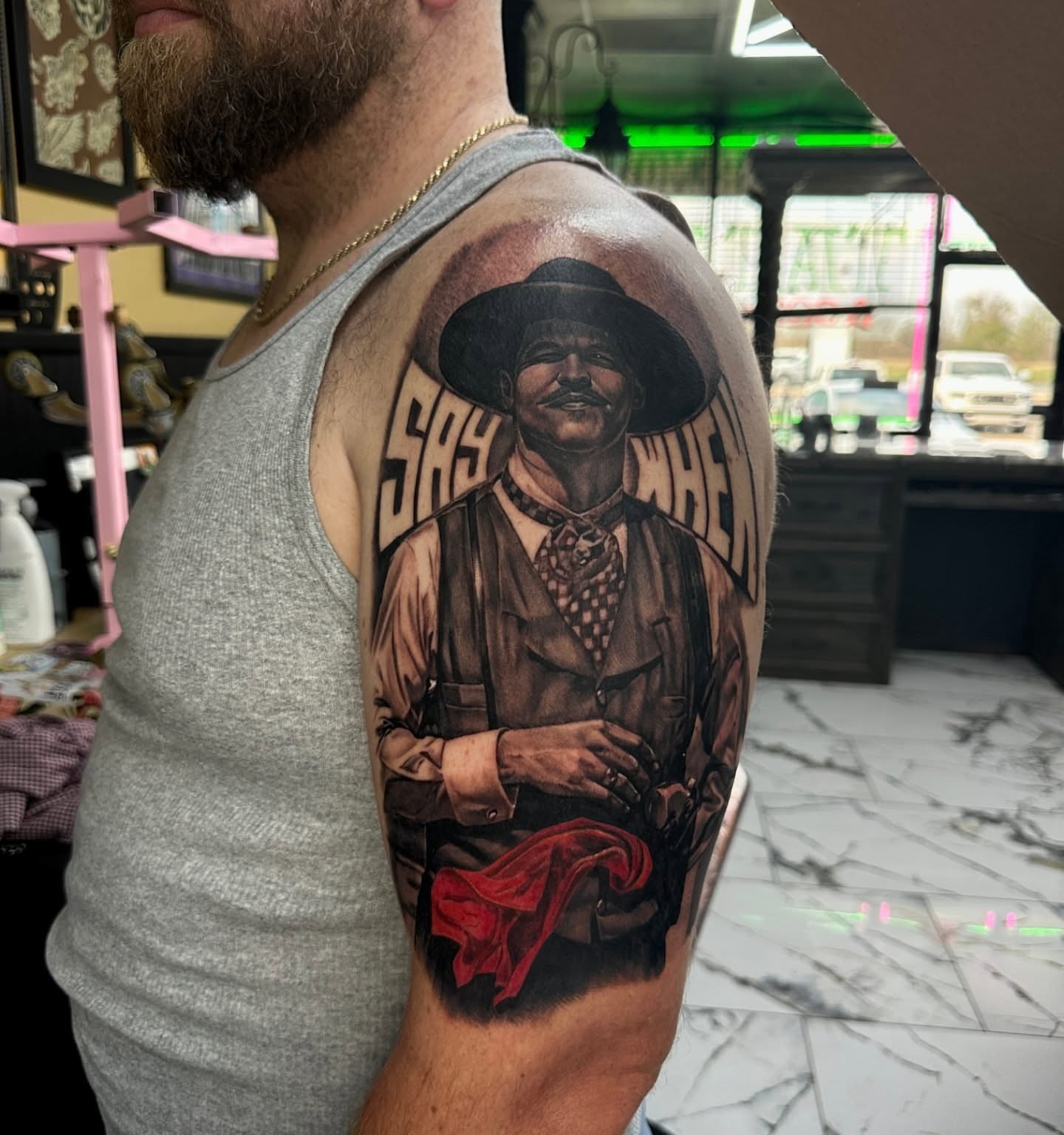 Saying 'SASQUATCH' realism tattoo on the upper arm by Billy Harris
