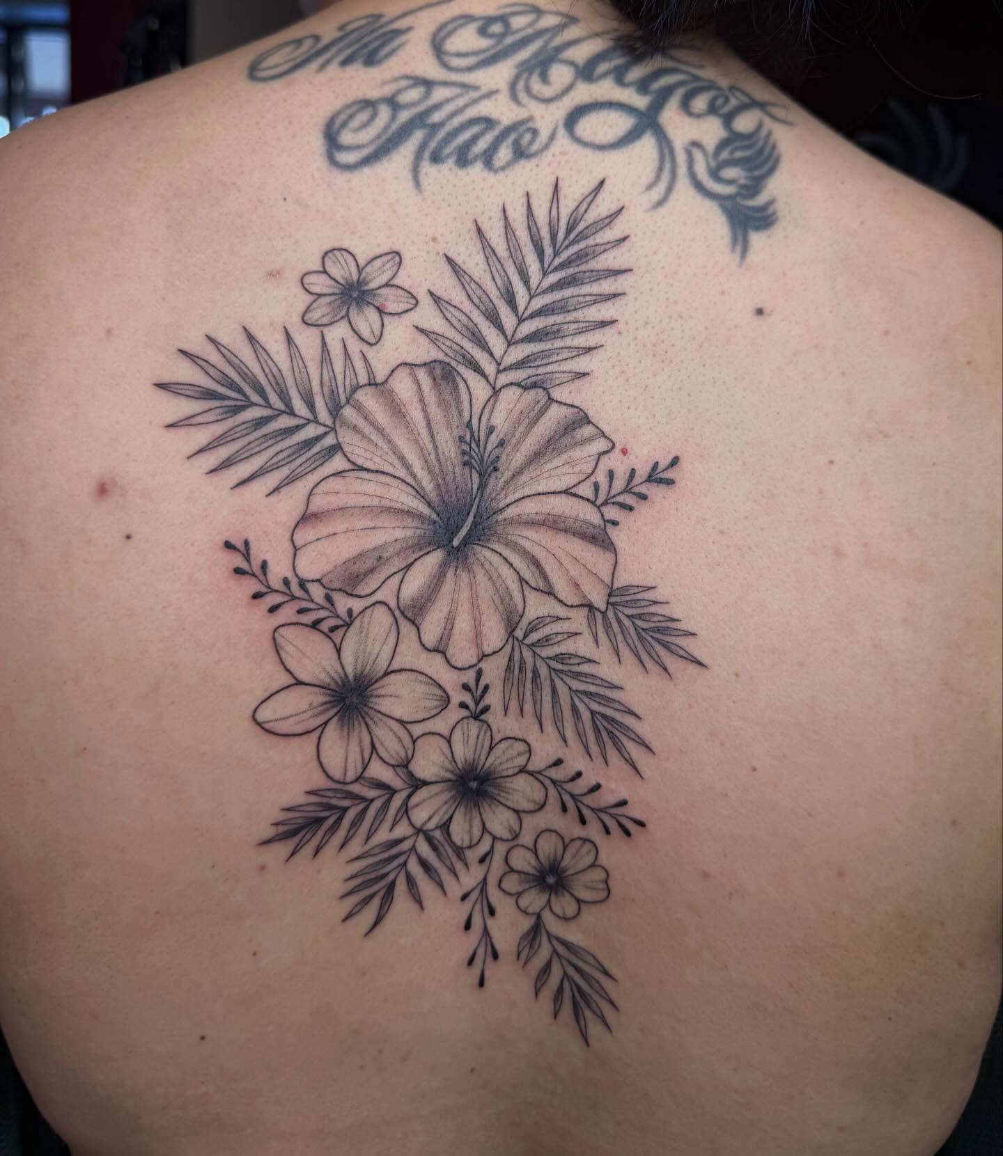 Hawaiian flowers black and grey tattoo on the back by Imani