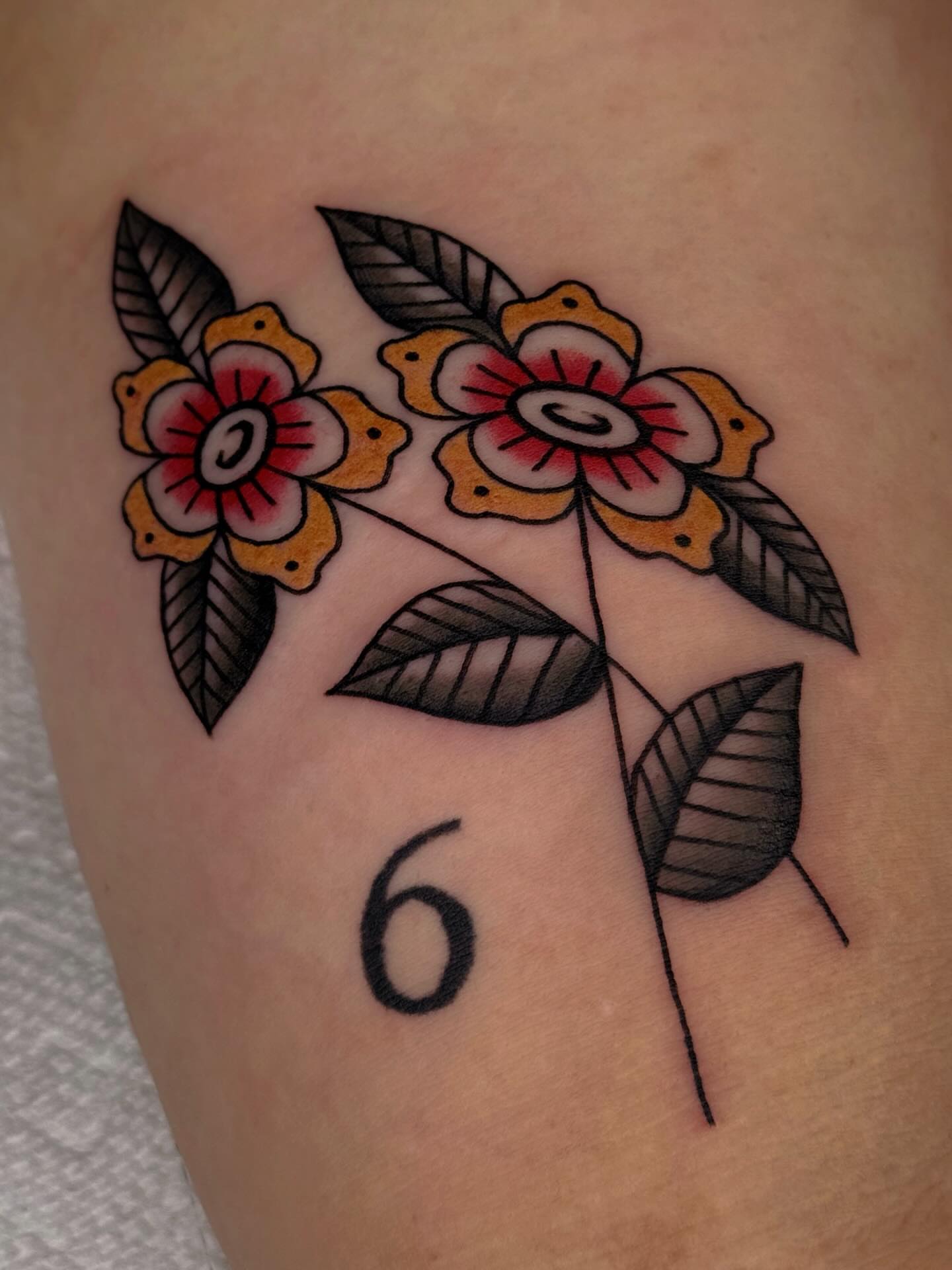 Flowers and number 6 American traditional tattoo on the forearm by Bridgette Carberry