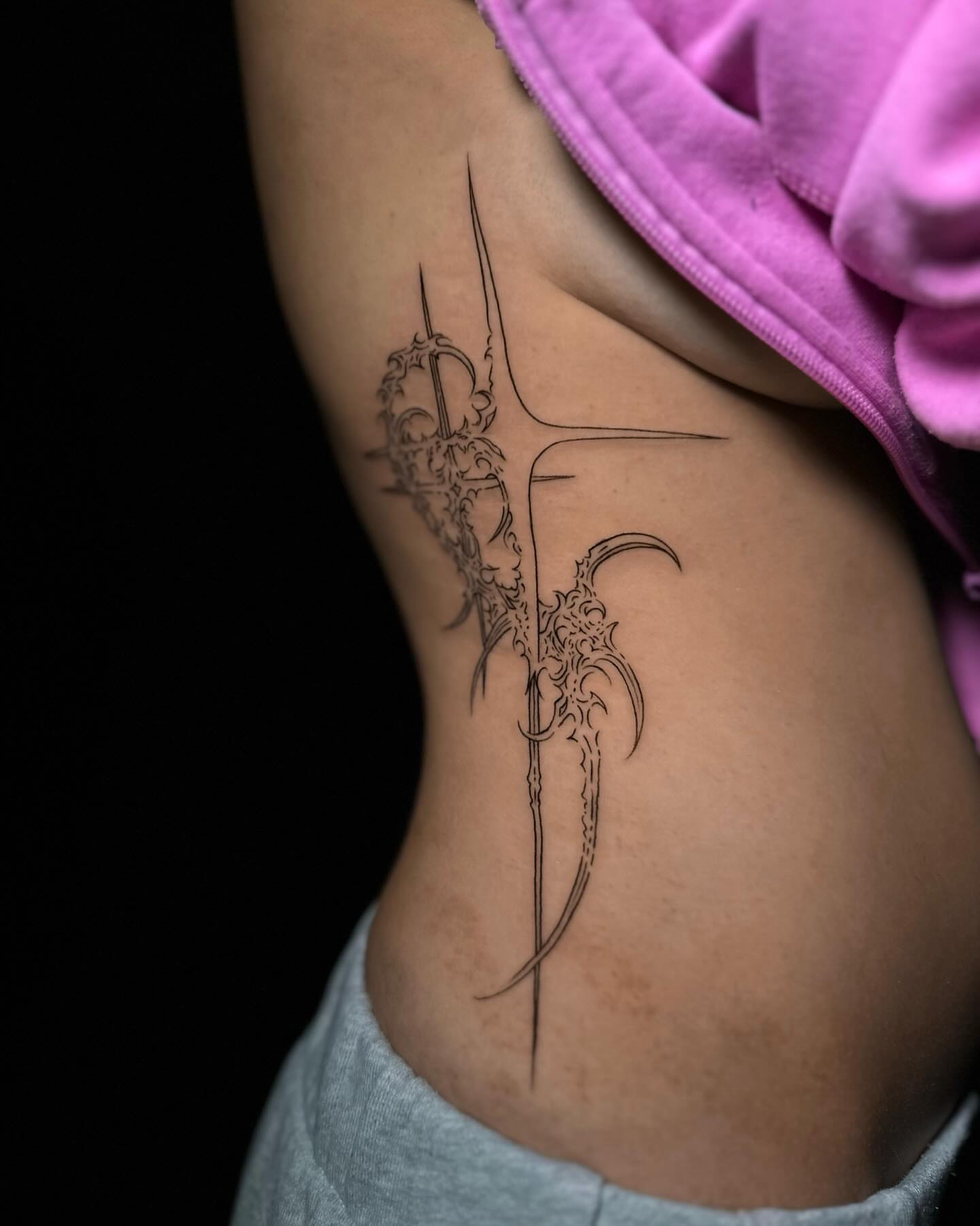 Cross with ornate details black and grey tattoo on the ribs by Frida Tattooista