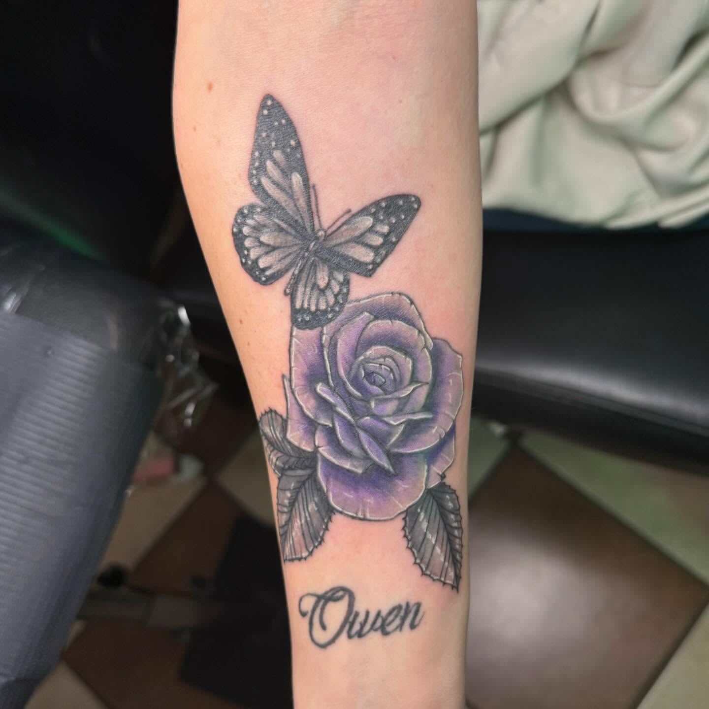 Purple rose with butterfly realism tattoo on the forearm by Nina Rush