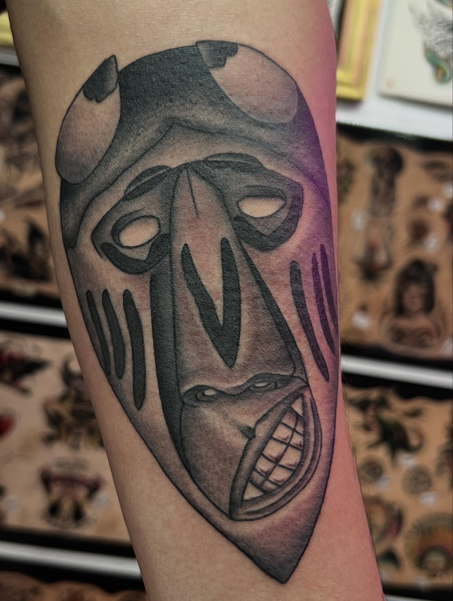Mask black and grey tattoo on the forearm by Charlie Campanella