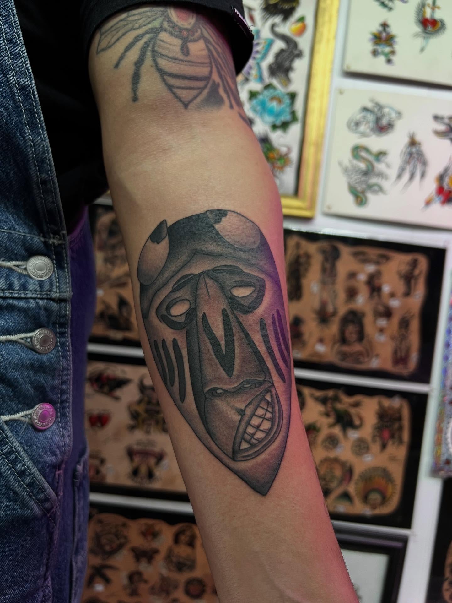 Mask black and grey tattoo on the forearm by Charlie Campanella