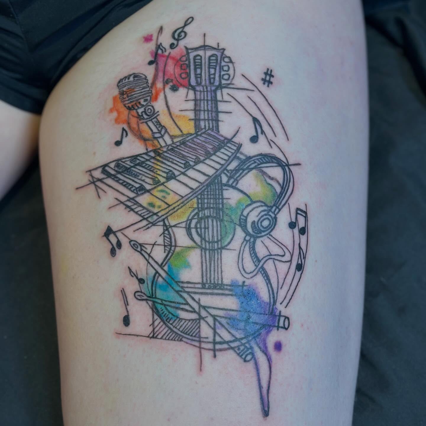 Music instruments watercolor tattoo on the thigh by Zen Forbes