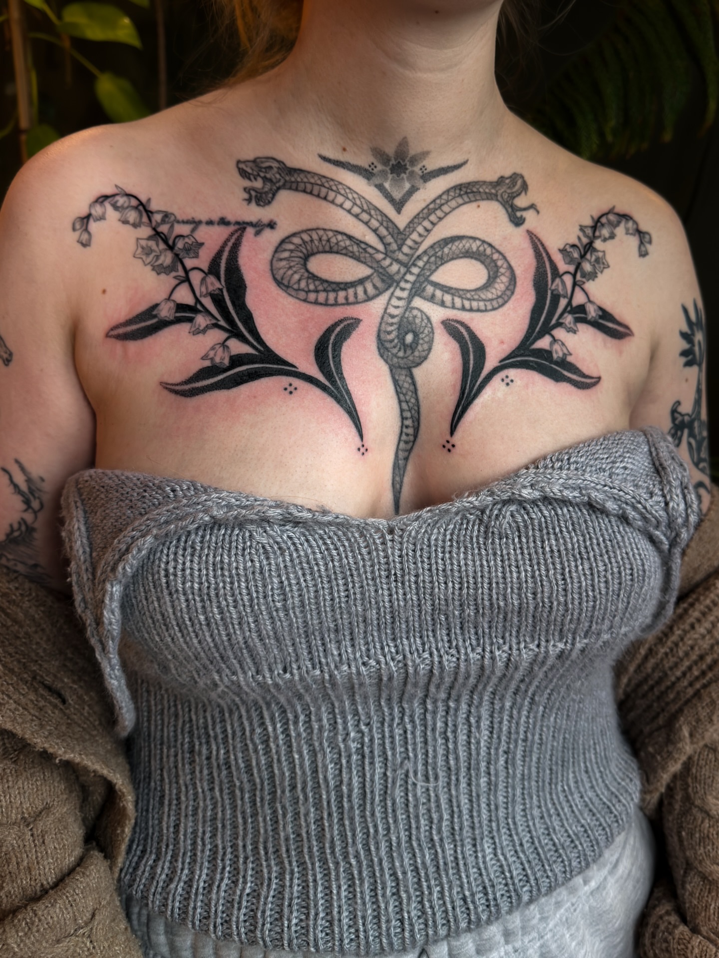 Snake and lily of the valley black and grey tattoo on the chest by Alexandra Gray