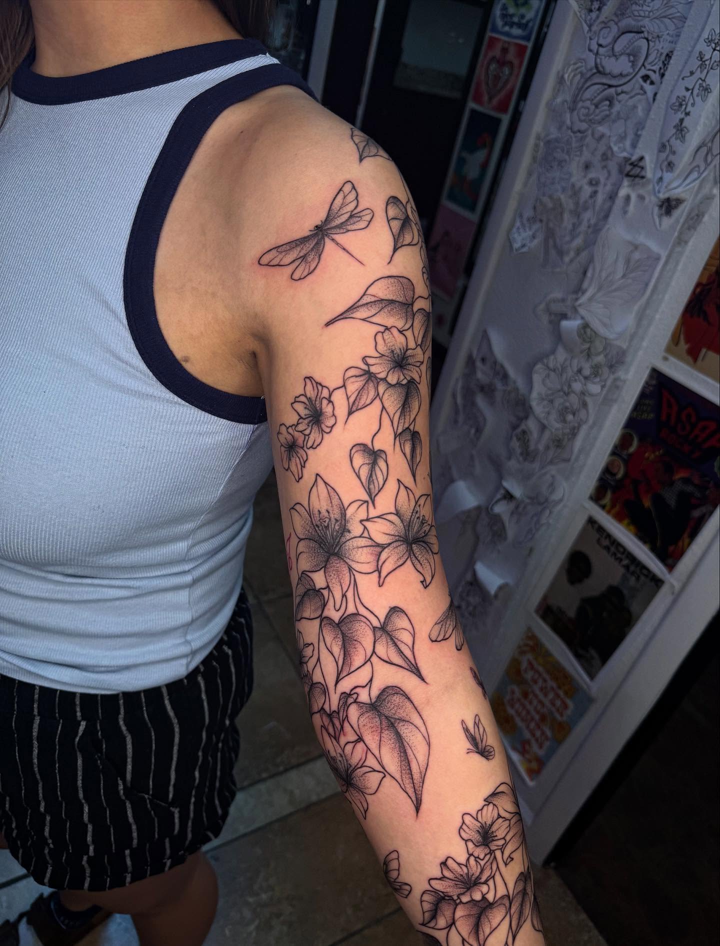 Floral and dragonfly black and grey tattoo on the forearm by McKenna Hughes