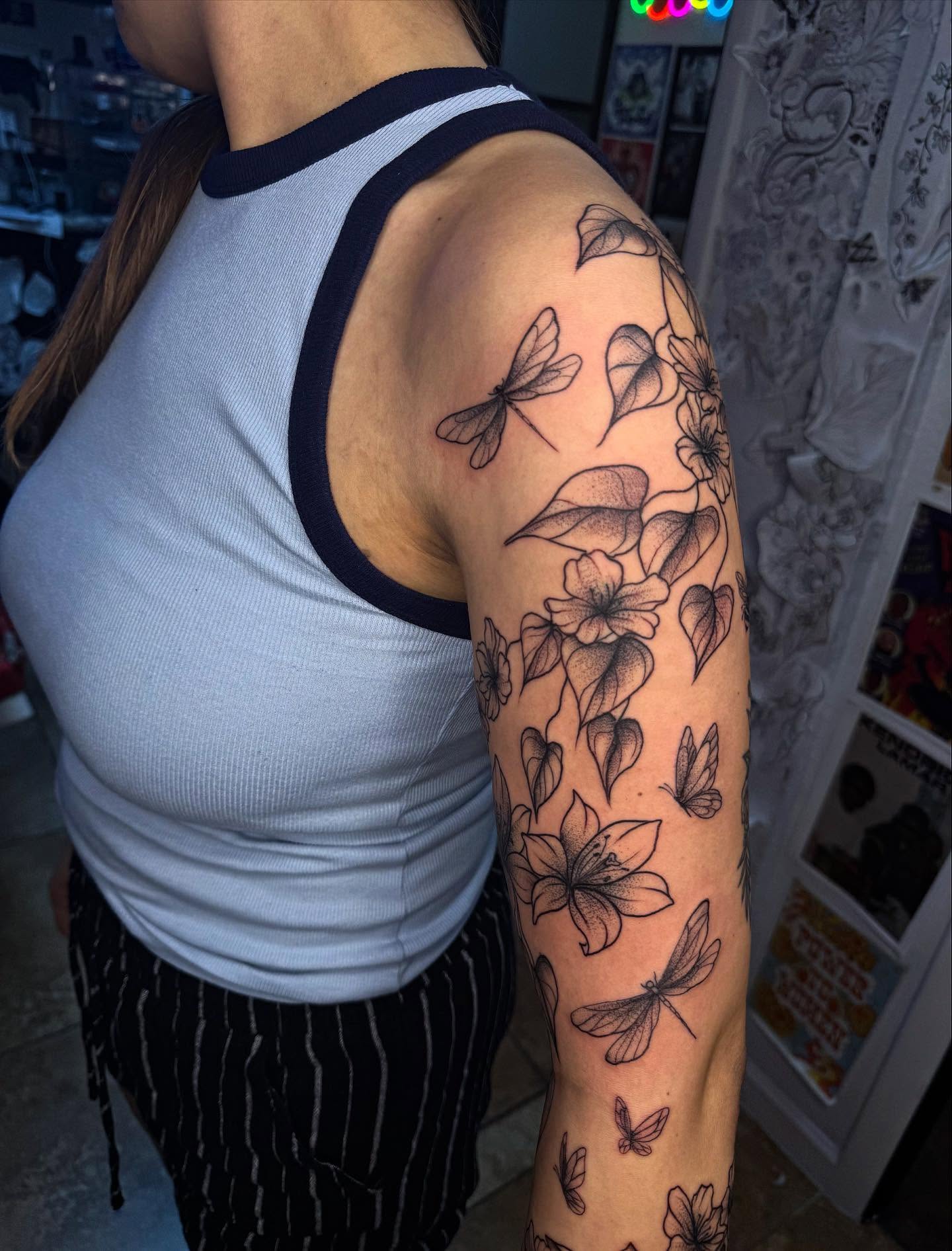 Flowers and butterflies dotwork tattoo on the upper arm by McKenna Hughes