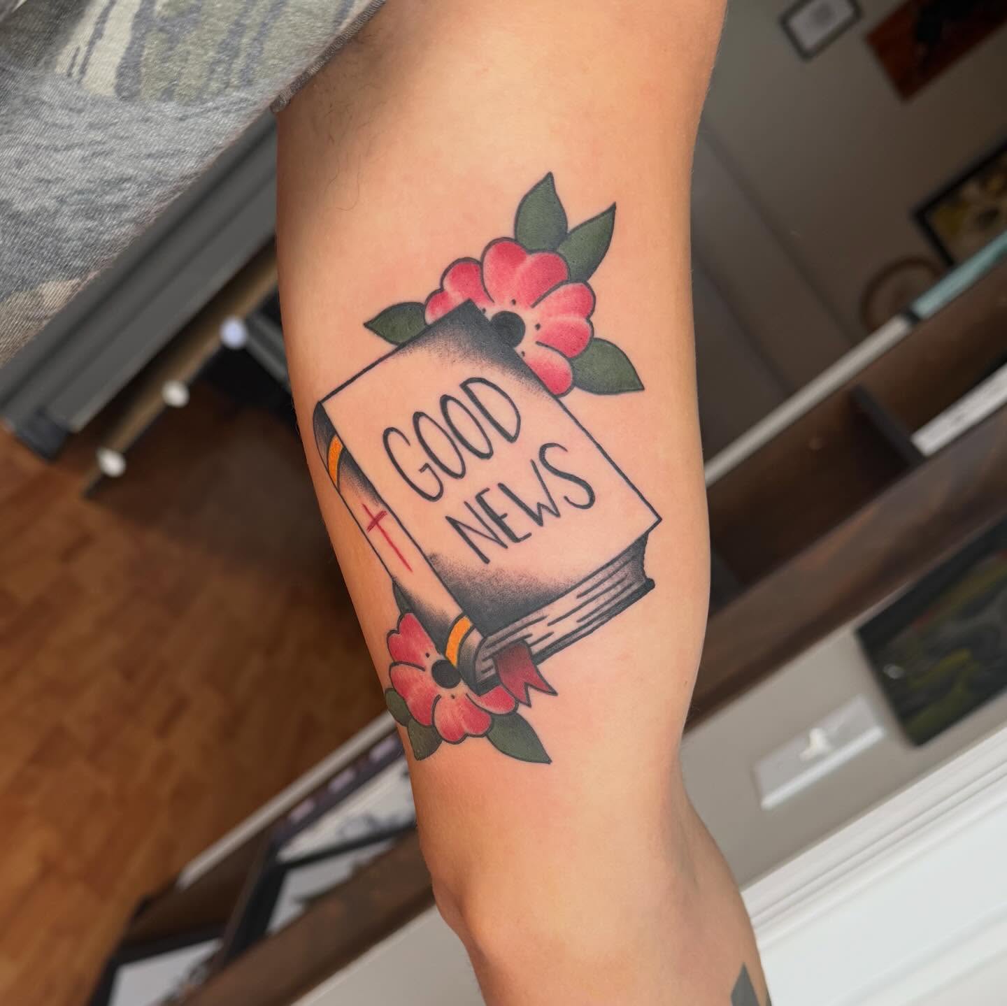 Book with 'GOOD NEWS' American traditional tattoo on the forearm by Matt Hattaway