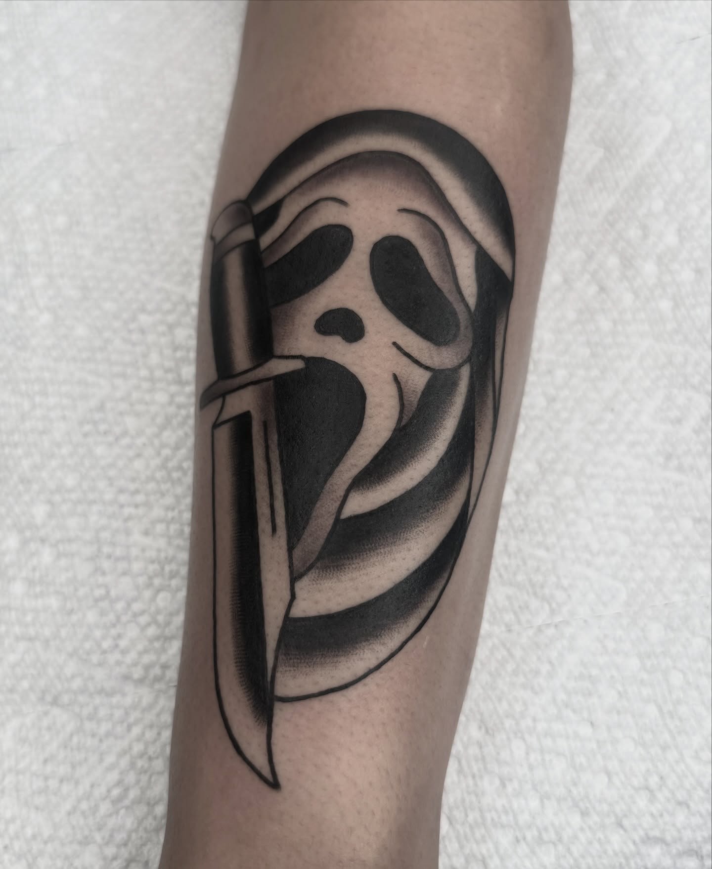 Scream mask black and grey tattoo on the forearm by Drew🕸️, Phoenix, Arizona