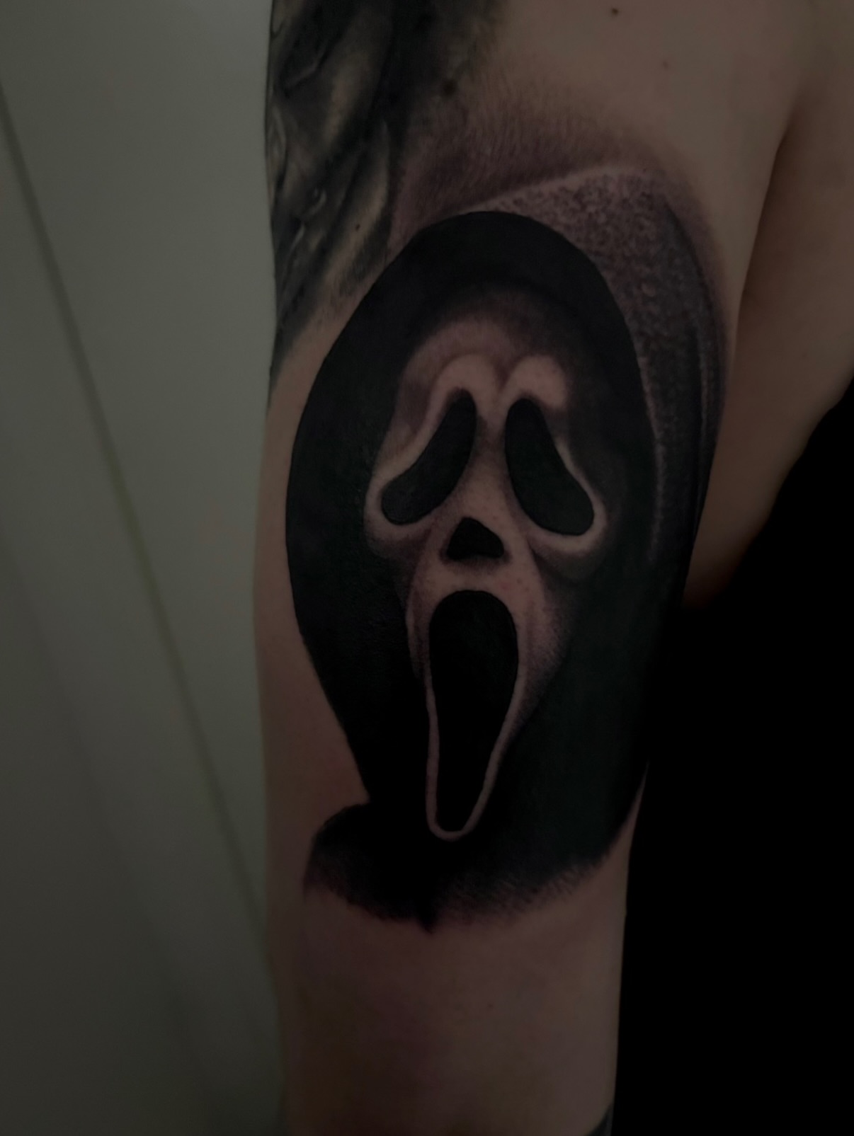 Scream mask black and grey tattoo on the forearm by Nick Campbell