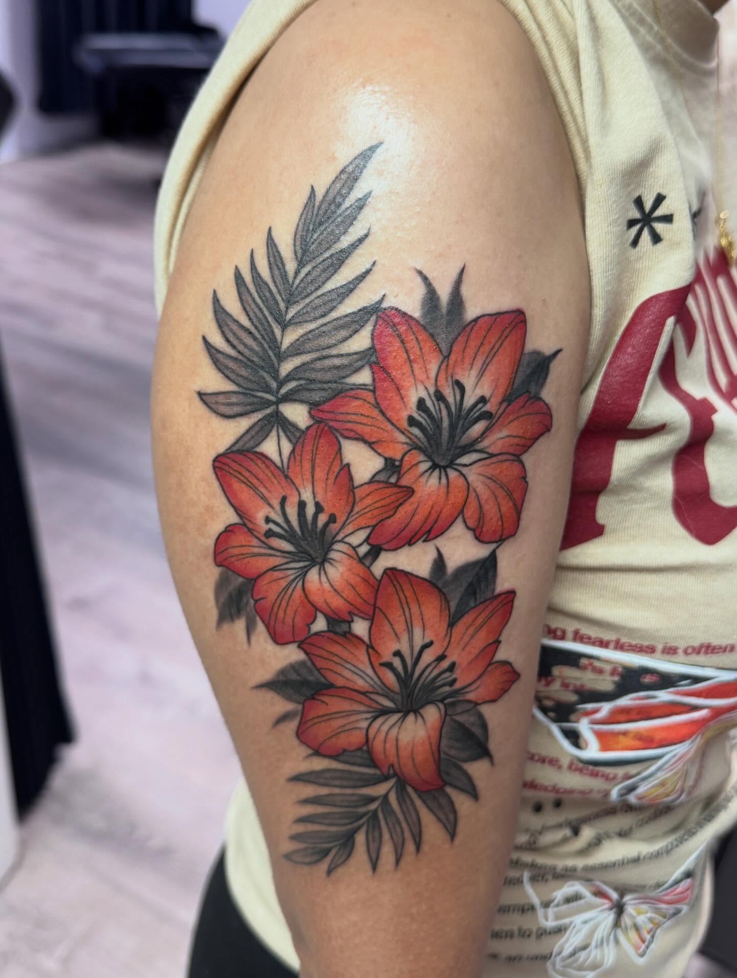 Lilies and ferns realism tattoo on the upper arm by Murbee