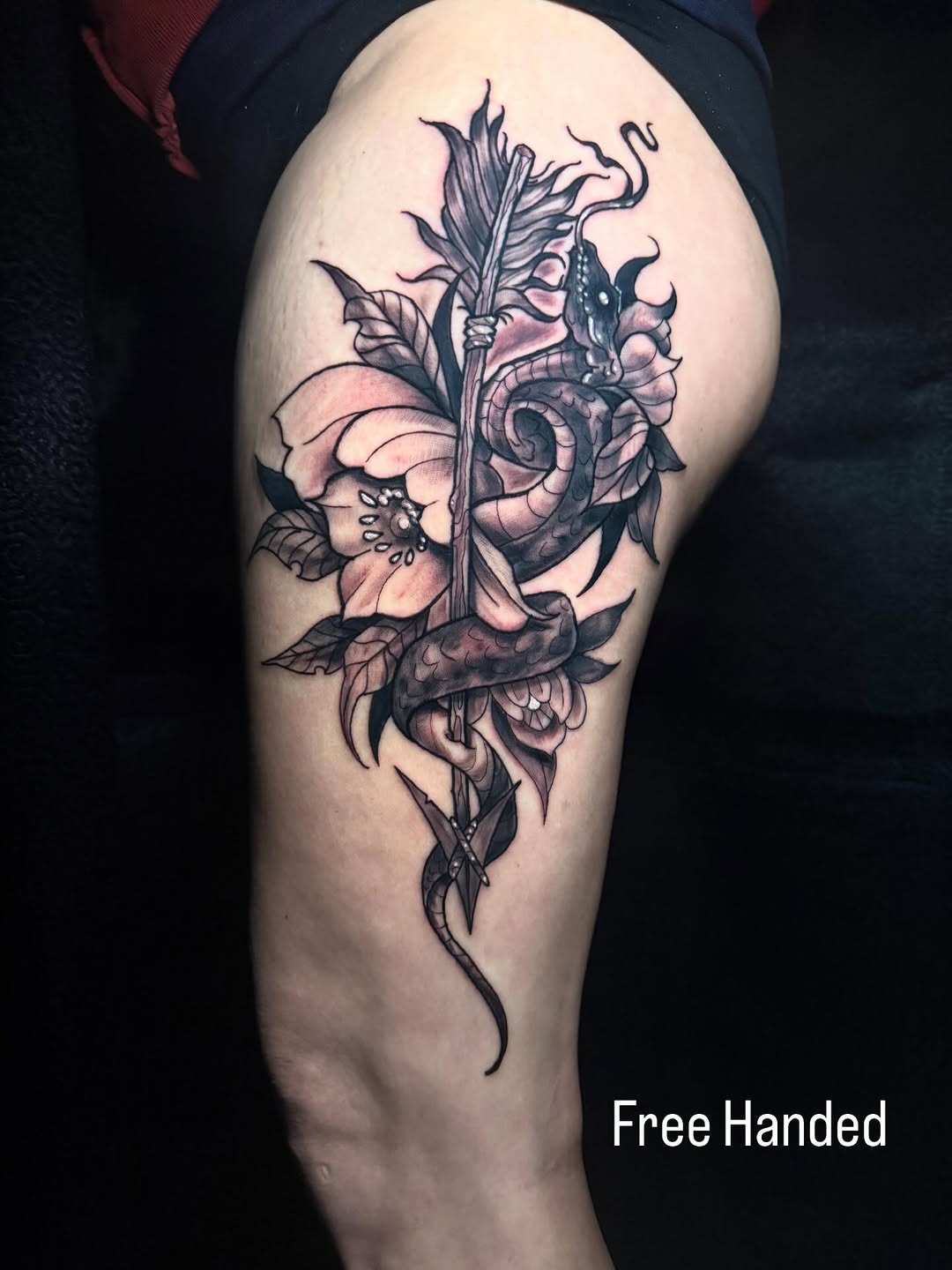 Snake, arrow, and flower realism tattoo on the thigh by Skunk Punk