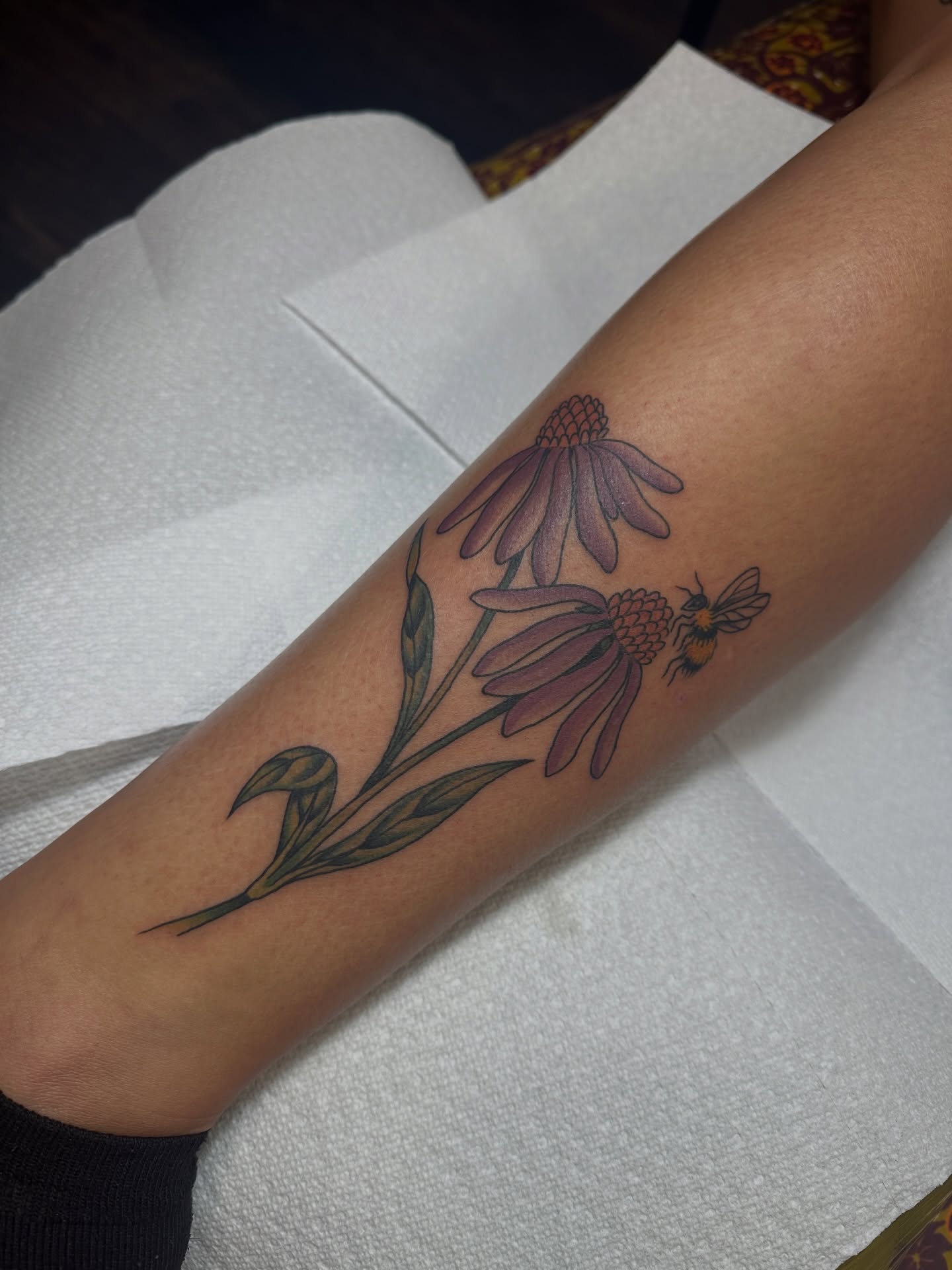 Purple coneflower and bee realism tattoo on the forearm by Hannah Eddy