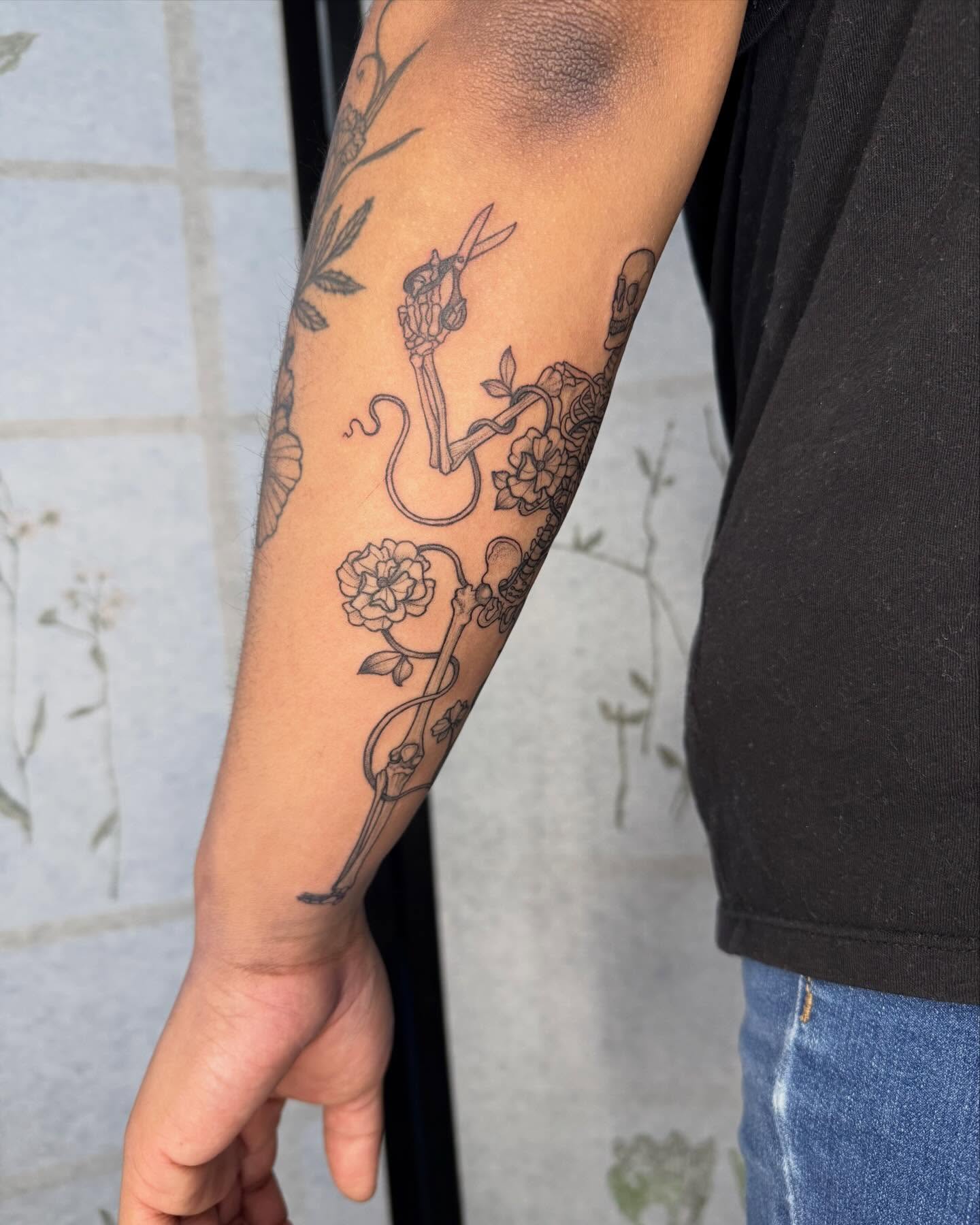 Snake and flowers black and grey tattoo on the forearm by Noelle Adrienne Tattoos