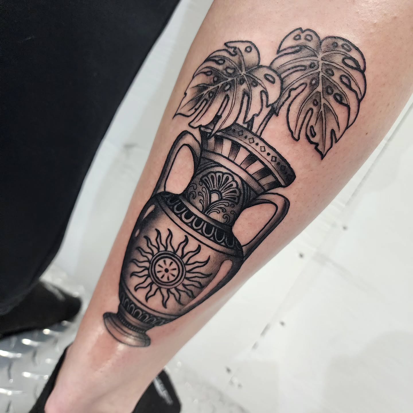 Vase with plant black and grey tattoo on the forearm by Robert Glover