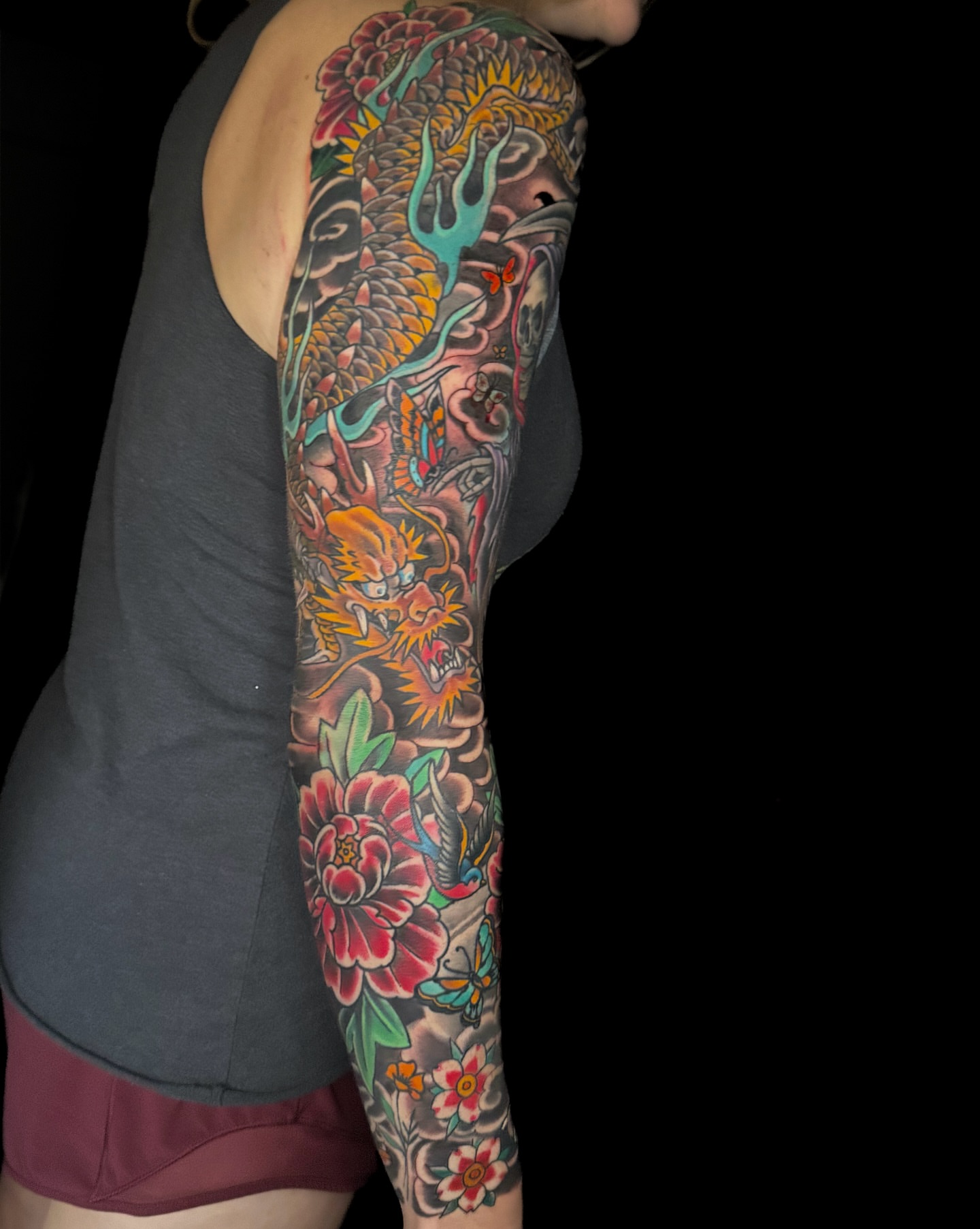 Dragon and floral American traditional tattoo on the upper arm by Chris Cockrill